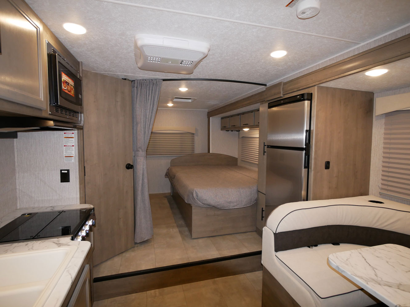 Inside this RV rental: kitchen, bedroom, dinette, and fridge. A compact, modern space for travel comfort.. Coachmen Freelander 23FS 2022