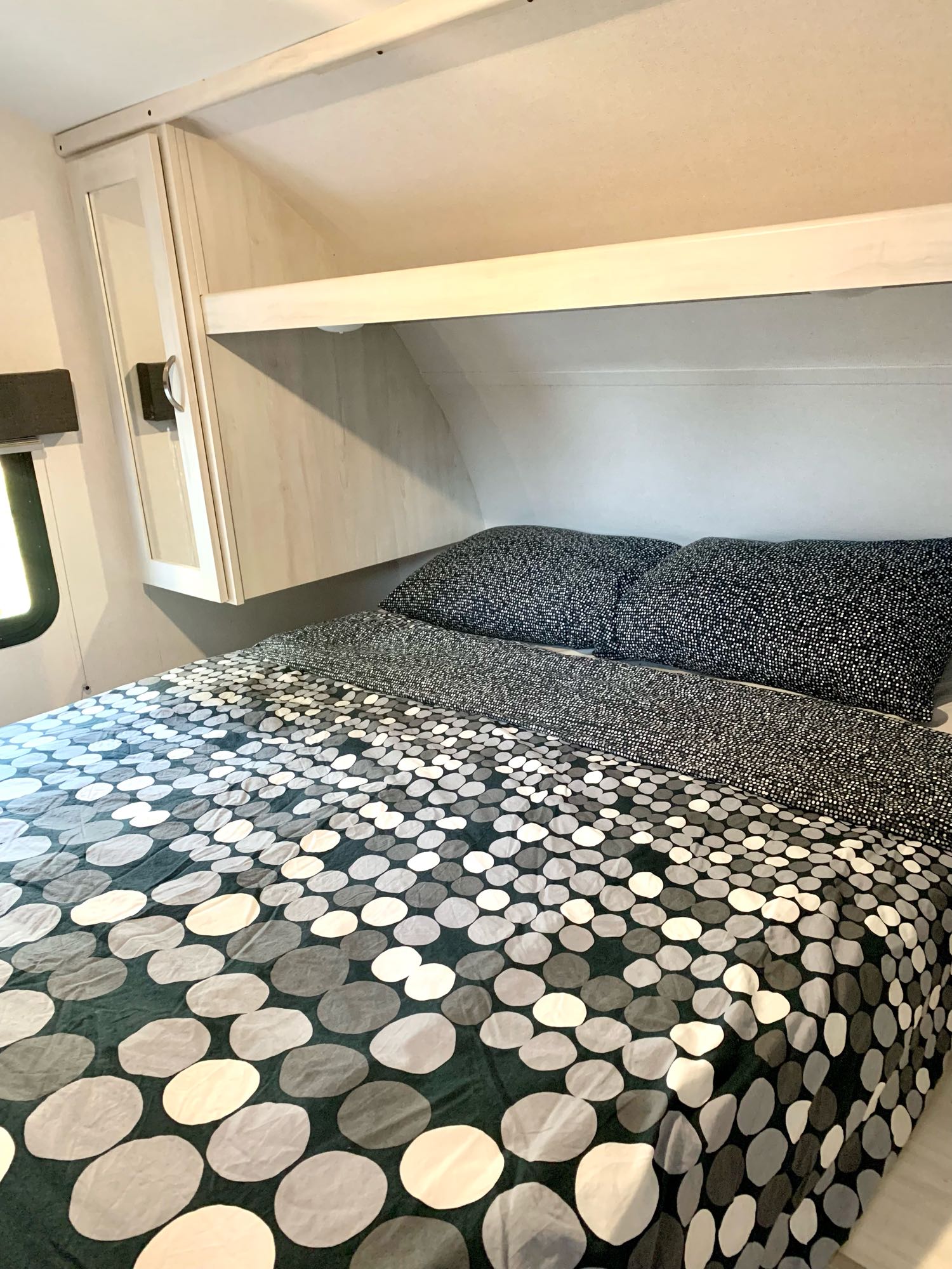 RV rental bedroom: A comfy bed with unique stone-patterned bedding & practical overhead storage.. Forest River Tracer 260BHSLE 2021