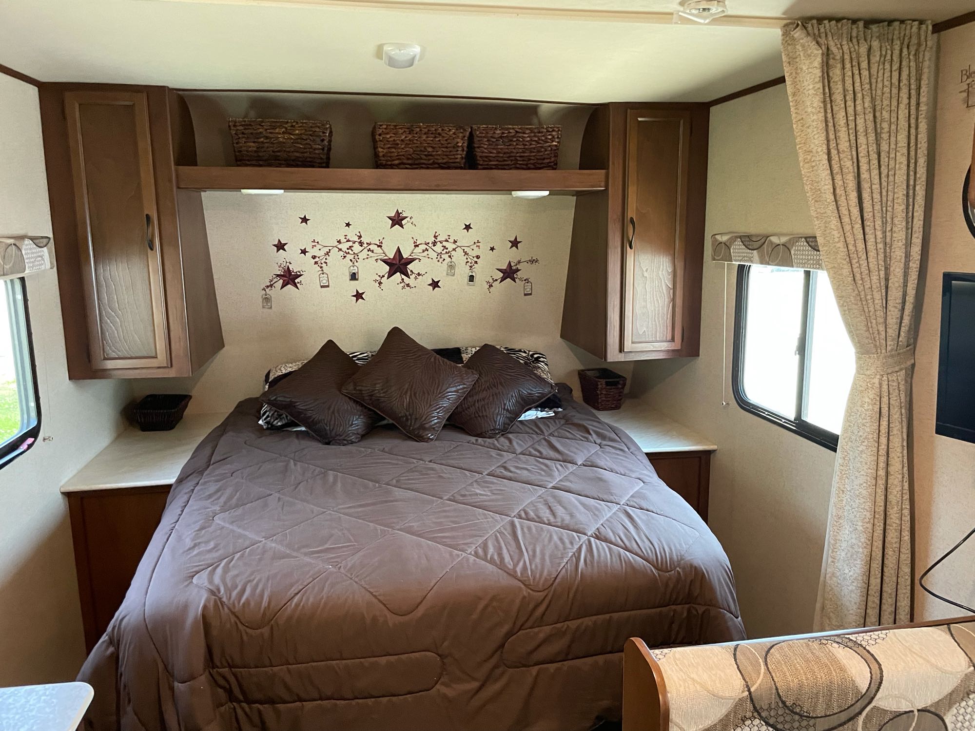 RV rental bedroom: cozy space with bed, overhead storage, and rustic star wall decor.. Jayco Jay Feather Ultra Lite 2015