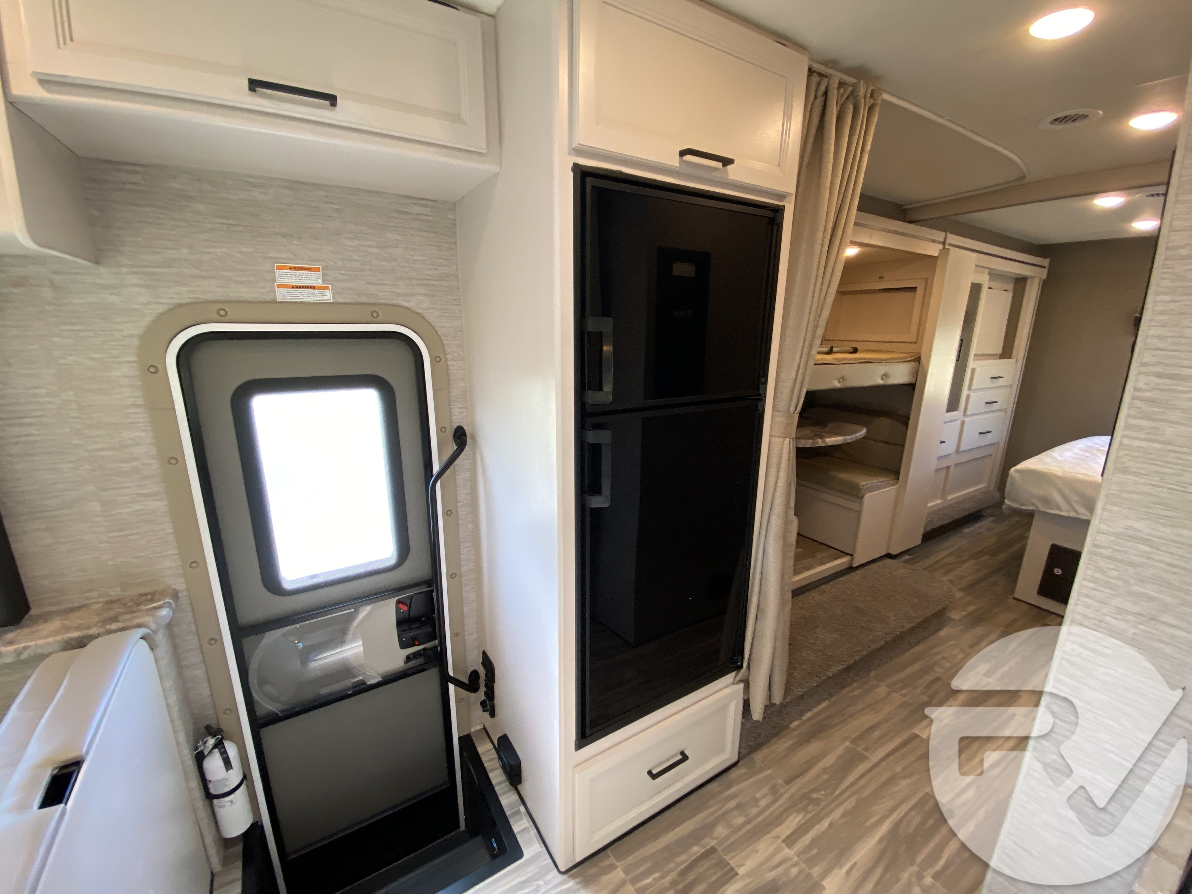 Spacious RV rental interior with an entry, full fridge, and bunk beds leading to a rear bedroom area.. Thor Motor Coach Four Winds 2021