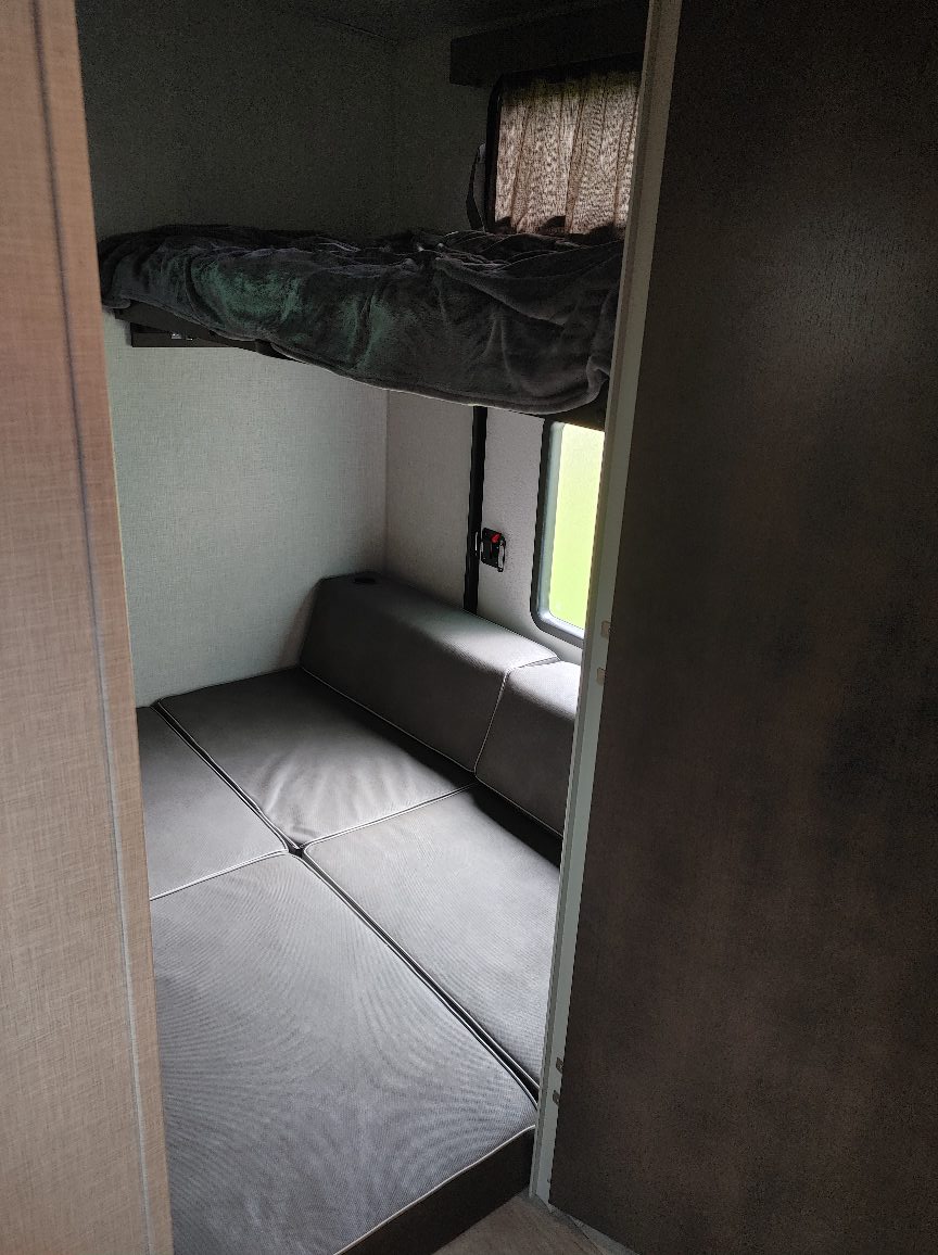 Comfortable bunk beds in an RV rental, featuring an upper bed & convertible lower sleeping area with window. Perfect for families.. Forest River Rockwood Ultra Lite 2021