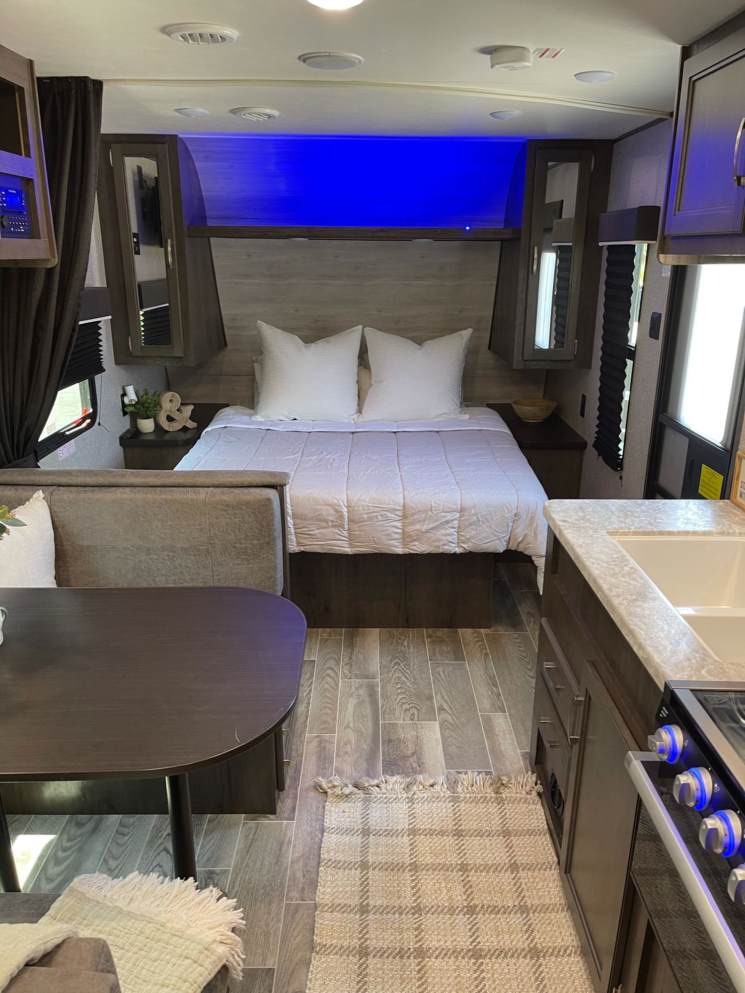 This cozy RV rental interior features a comfortable bedroom with blue accent lighting, a dinette, and a neat kitchen. Your travel home!. Jayco Jayflight 224bhw 2021