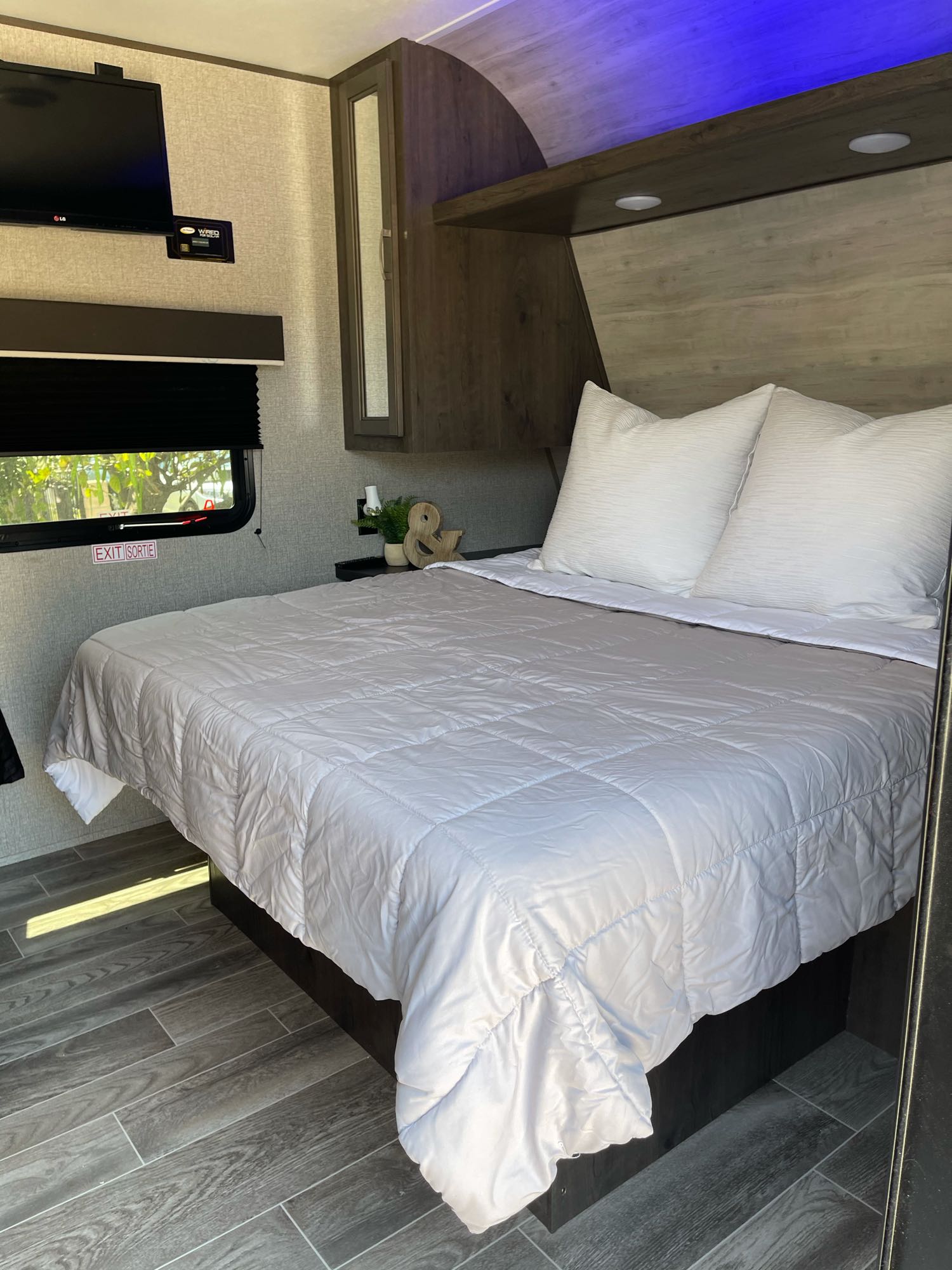 RV rental's modern bedroom: comfy bed, sleek wood-look interior, TV, and ambient blue lighting.. Jayco Jayflight 224bhw 2021