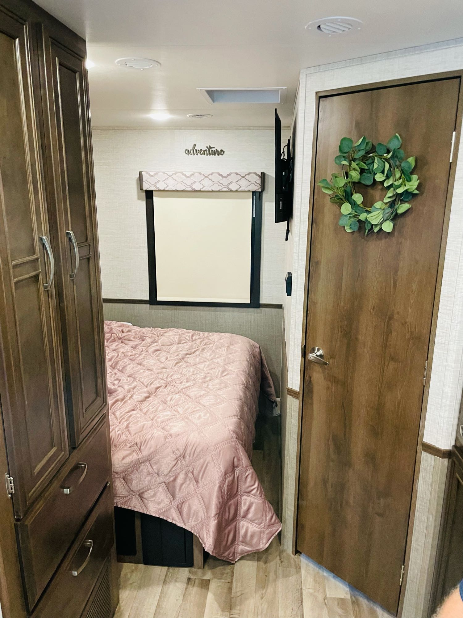 Modern RV rental bedroom, featuring a comfy bed, efficient storage, and stylish decor like an "adventure" sign.. Jayco Alante 2021