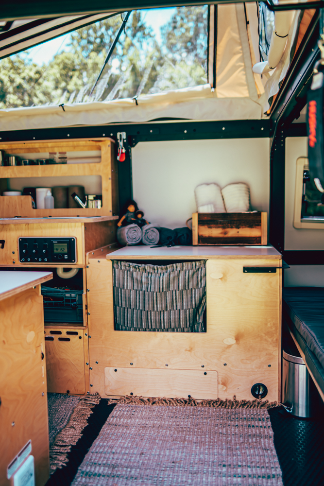 Cozy RV rental interior: custom wood cabinetry, shelves, and a control panel for comfortable camper adventures.. TAXA Outdoors Mantis Camper 2020