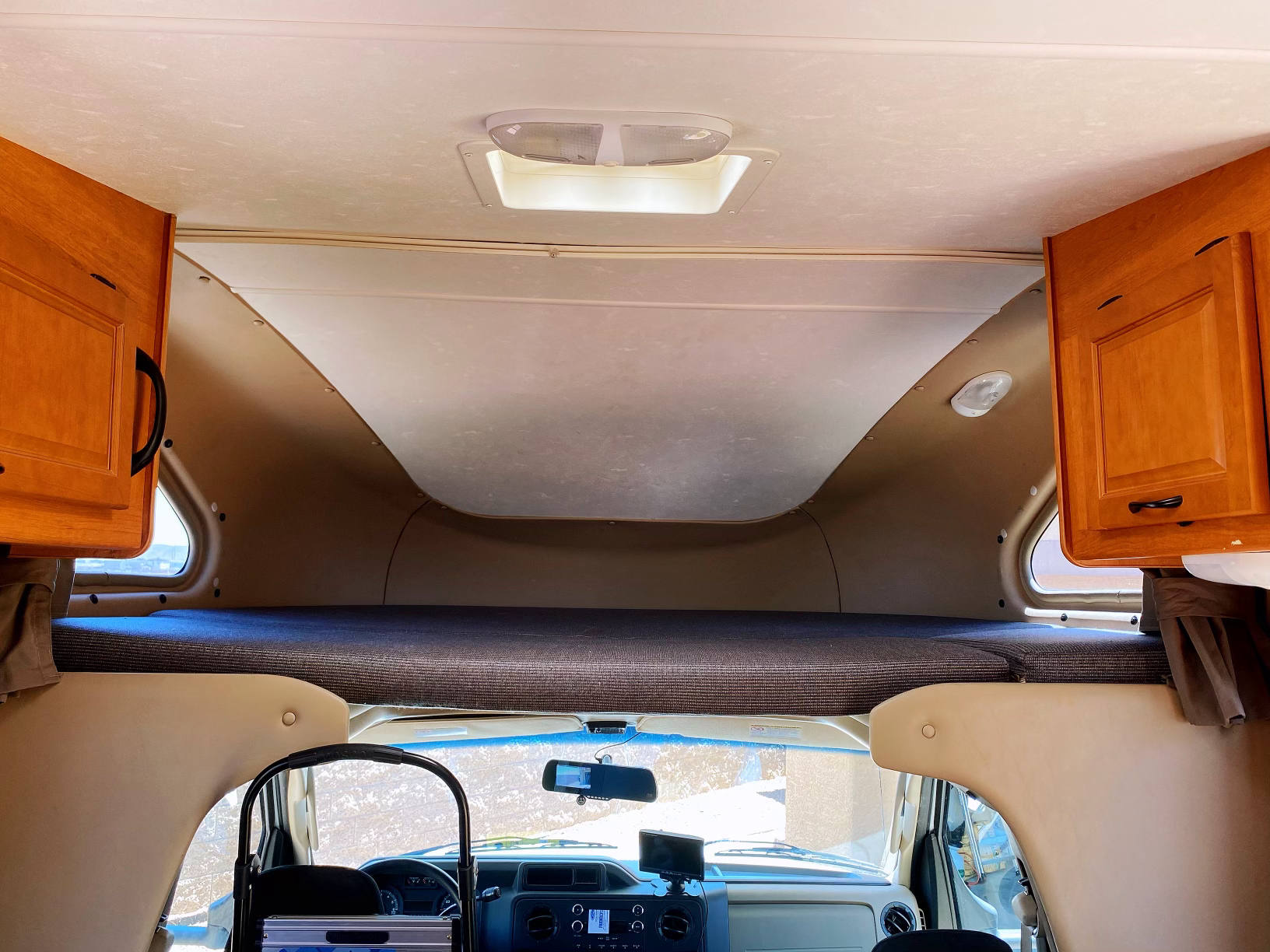Inside an rv rental: Cozy cab-over bunk bed with overhead cabinets, offering extra sleeping space above the driver's area.. Other Other 2014