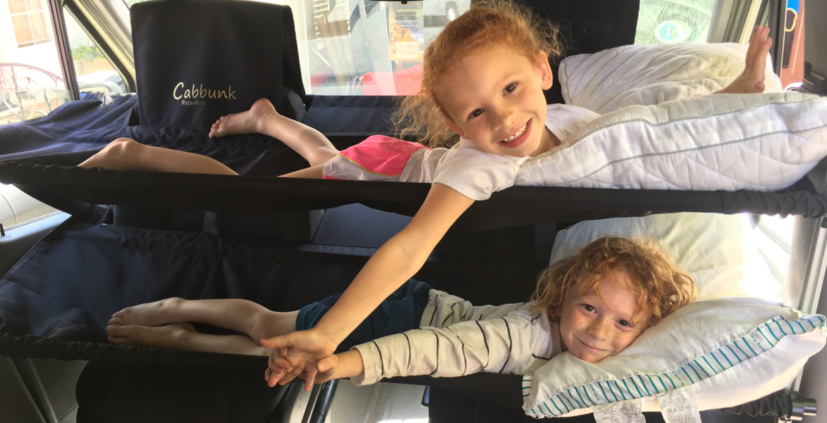Two children smile, comfy on Cabbunk bunk beds in an RV rental. Great compact sleeping for family adventures.. Other Sprinter 2016