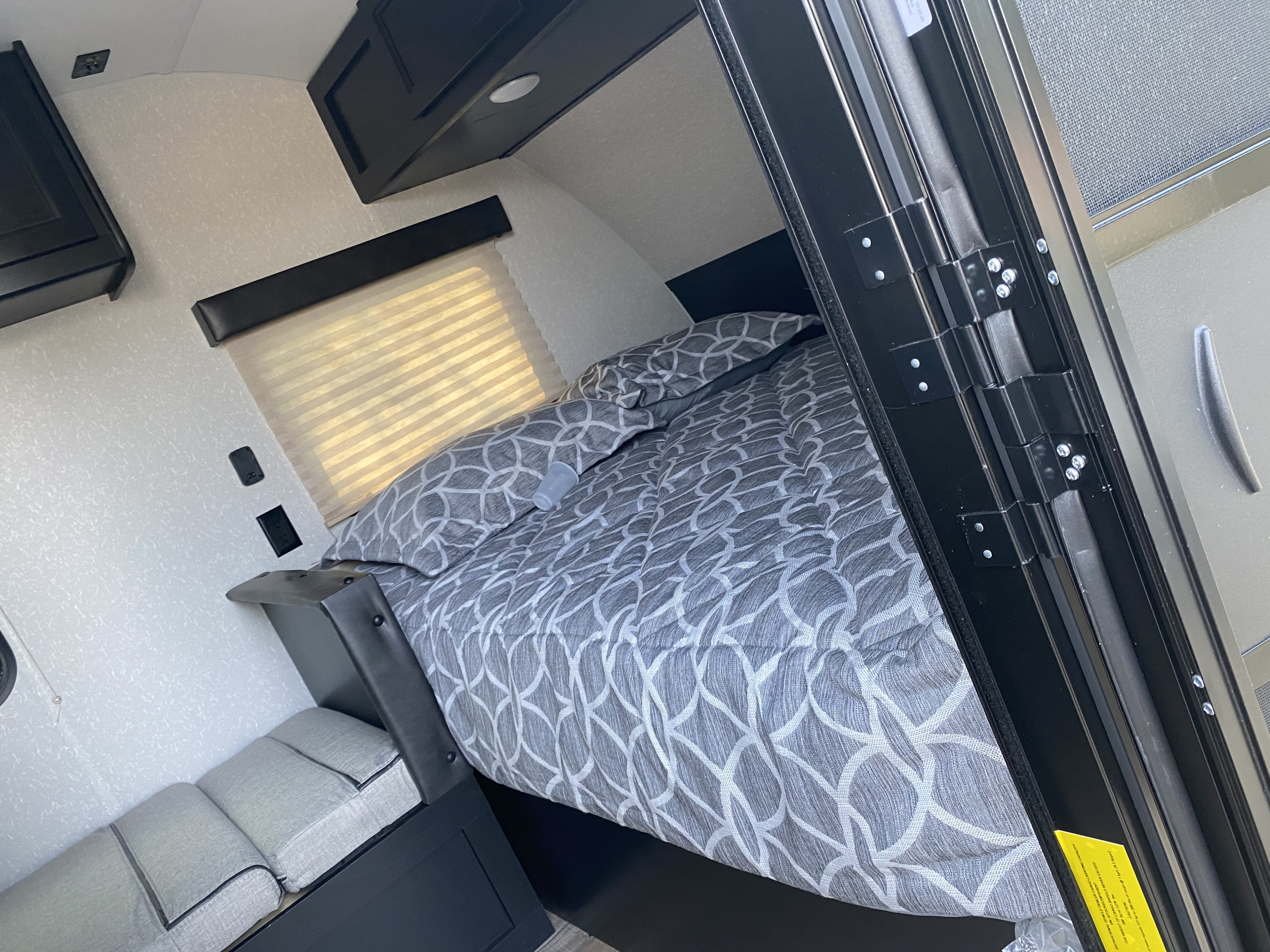 Cozy RV rental bedroom with a comfy patterned bed, window, and storage, perfect for your next road trip.. Forest River Cherokee Wolf Pup 2021