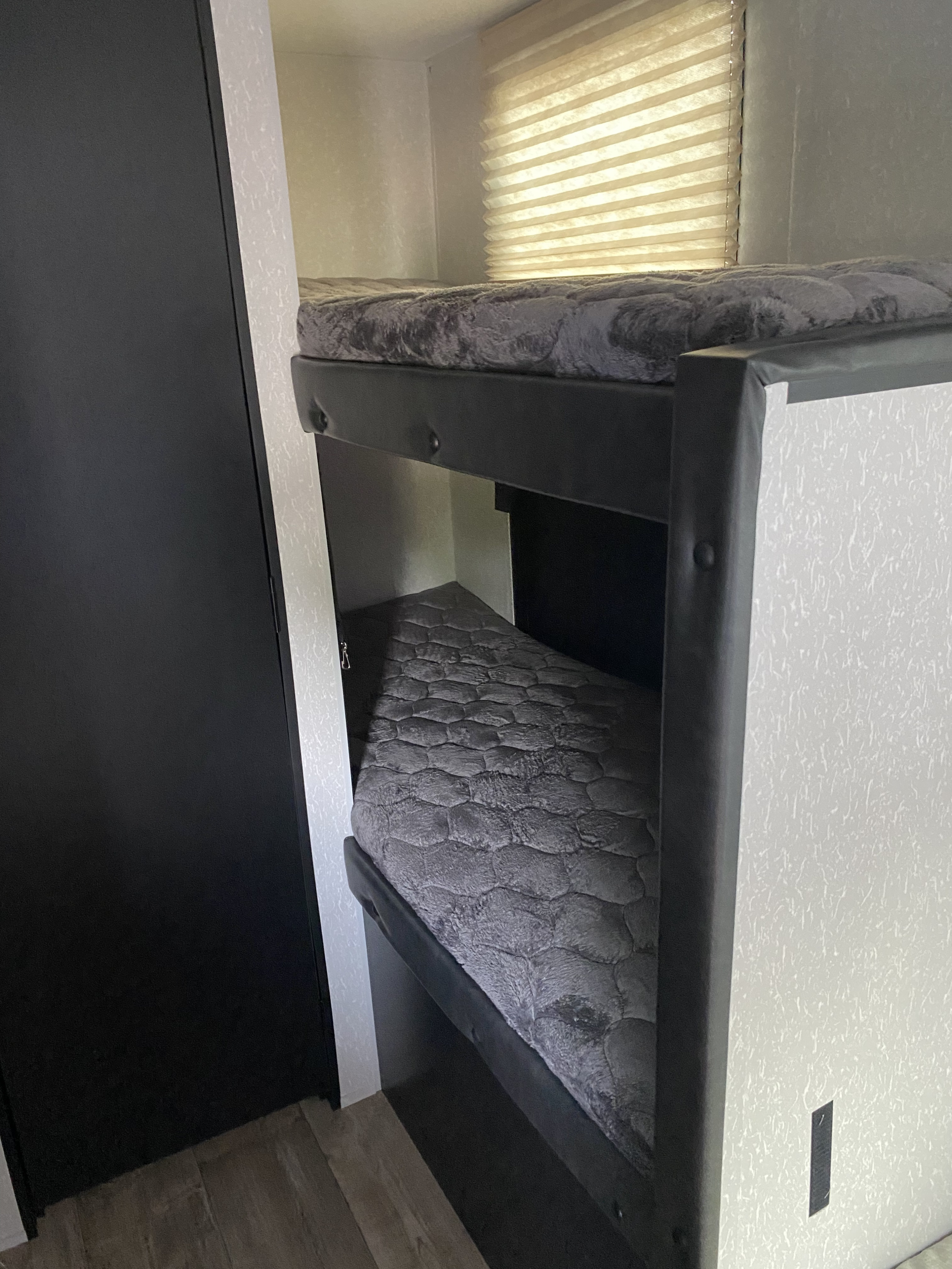 Explore this RV rental's comfy bunk beds! A practical interior sleeping area with grey mattresses & window blinds.. Forest River Cherokee Wolf Pup 2021