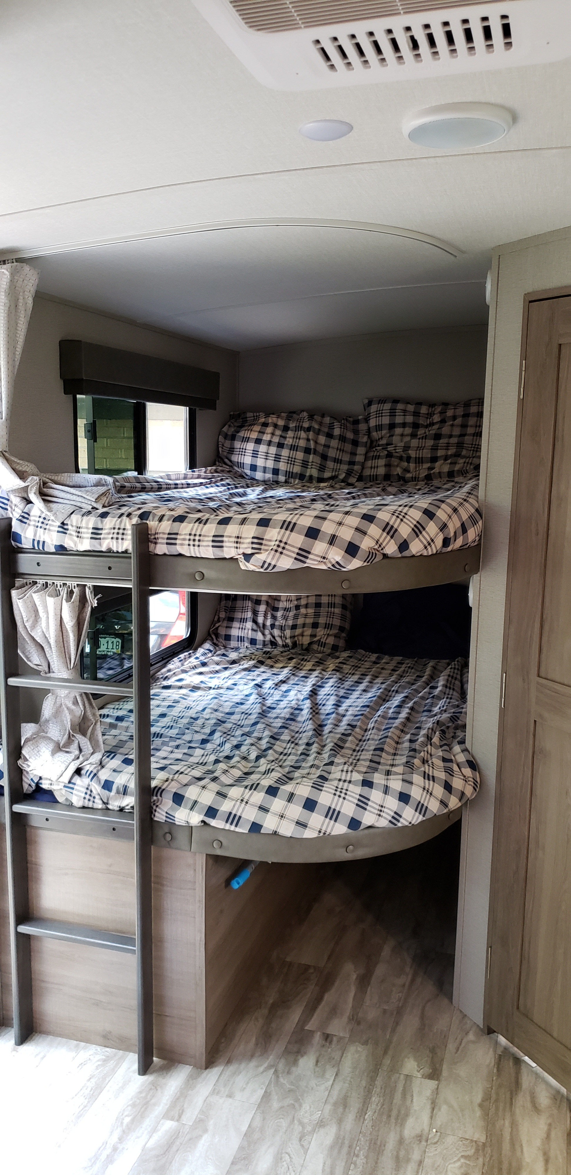 RV rental interior: comfortable bunk beds with blue plaid bedding, a ladder, window, and wood-look flooring.. Grand Design Imagine 2400BH 2021