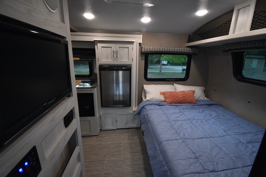 Cozy RV rental interior featuring a bedroom area, small kitchen with a refrigerator, and a mounted flat-screen TV.. Forest River Flagstaff E-Pro 2019