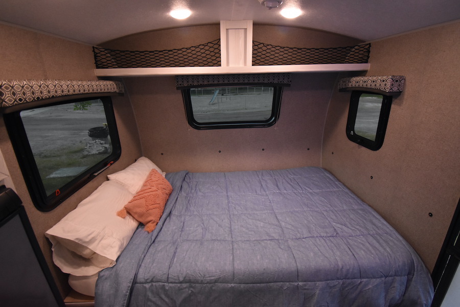 Cozy interior of an RV rental: a compact bedroom with a bed, windows, and storage nets, ideal for travel.. Forest River Flagstaff E-Pro 2019