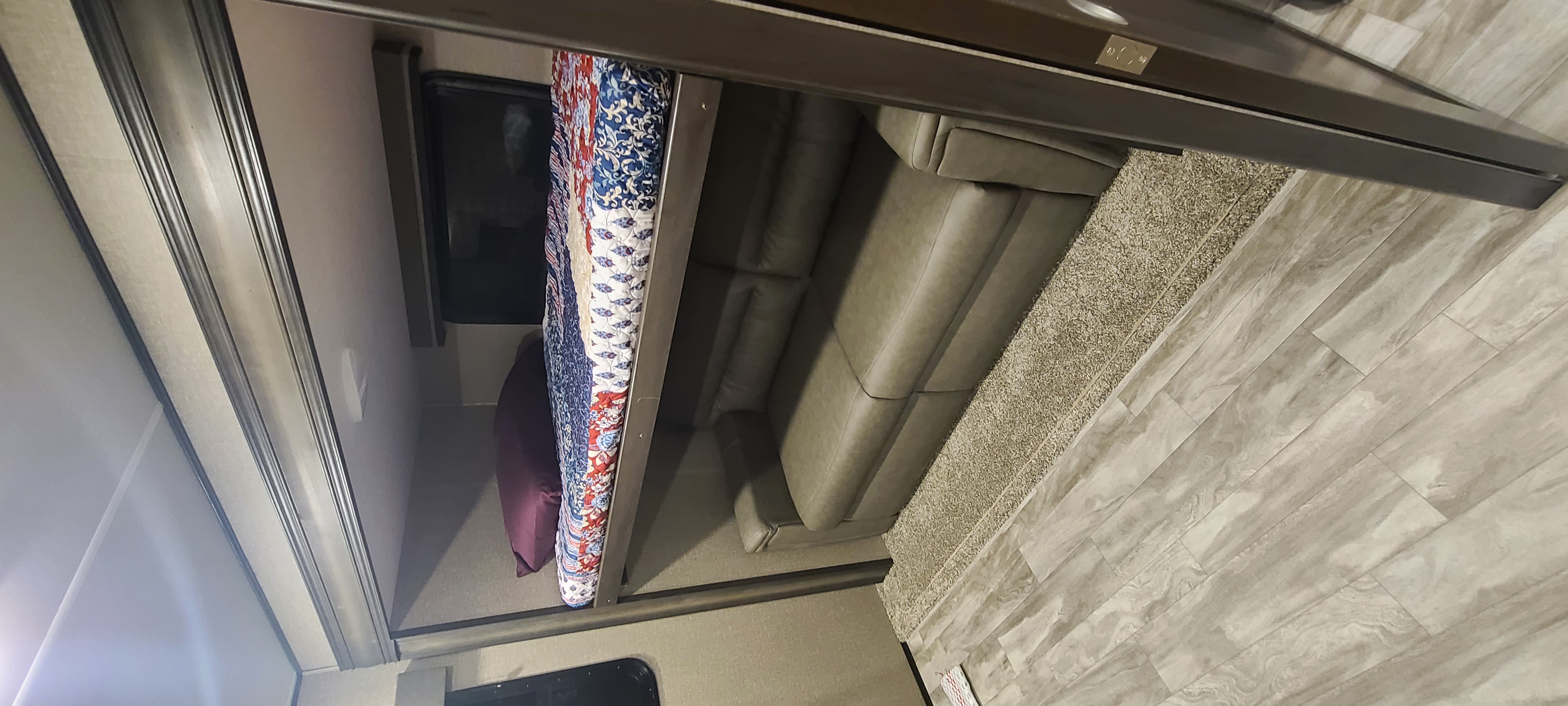 Cozy RV rental interior showcasing bunk beds, a plush sofa, and wood-look flooring with a rug.. Grand Design Reflection 2022