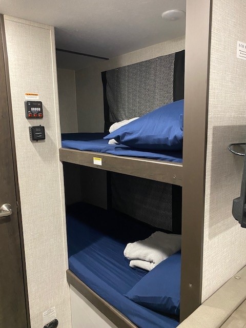 Cozy bunk beds with blue bedding and towels are ready in this RV rental, providing comfortable, compact sleeping.. Keystone Bullet 2021