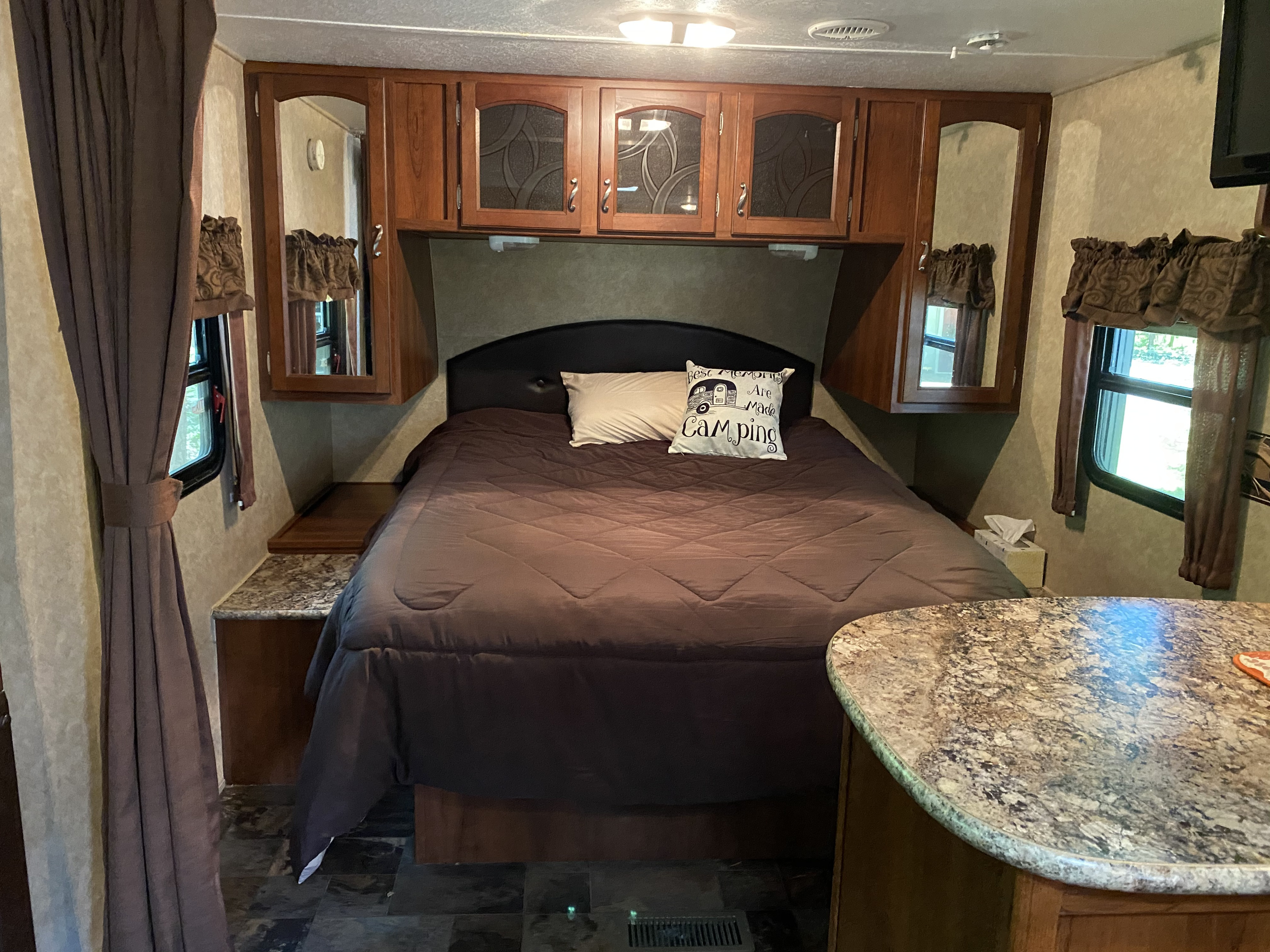 Spacious RV rental bedroom features a comfy bed, wood cabinets, and windows, offering a cozy retreat on wheels.. Forest River Tracer 2014