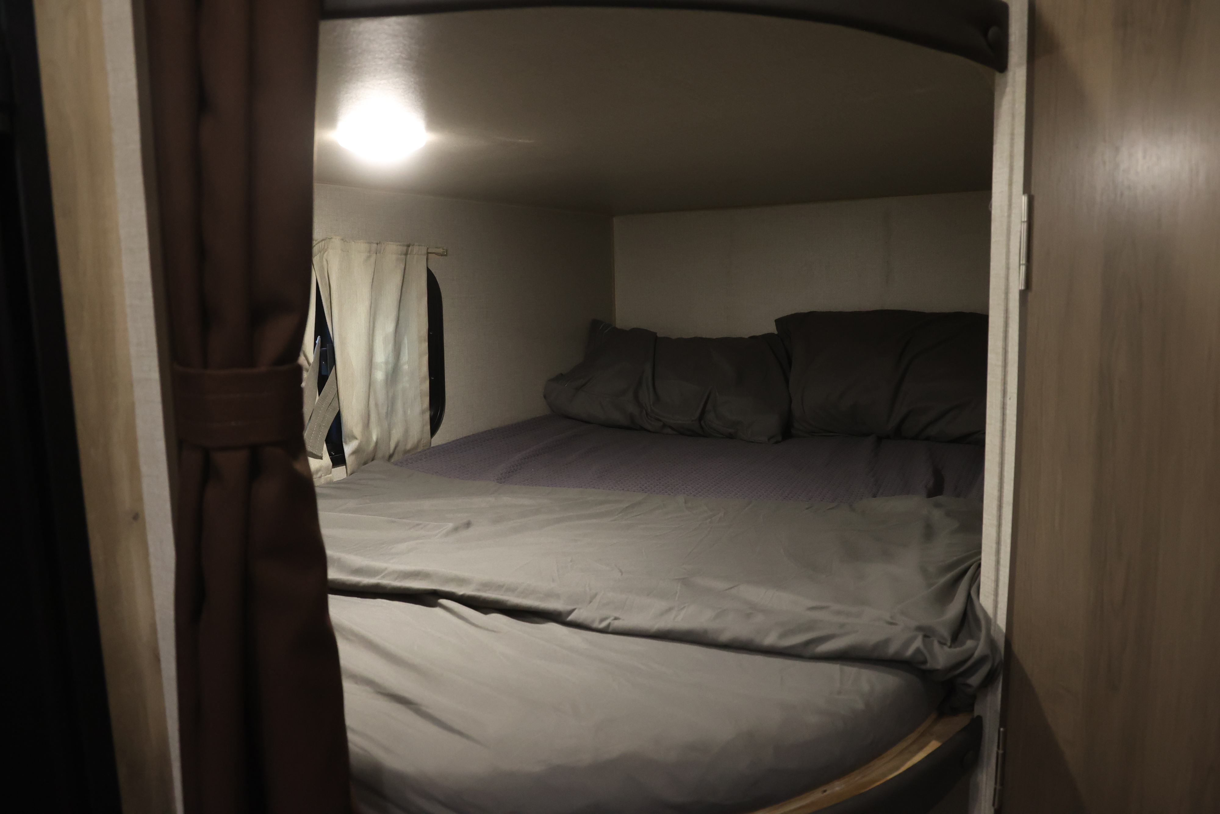 Cozy RV rental bedroom nook with comfy bed, pillows, and ambient light, ideal for travel.. Coachmen Catalina 2021
