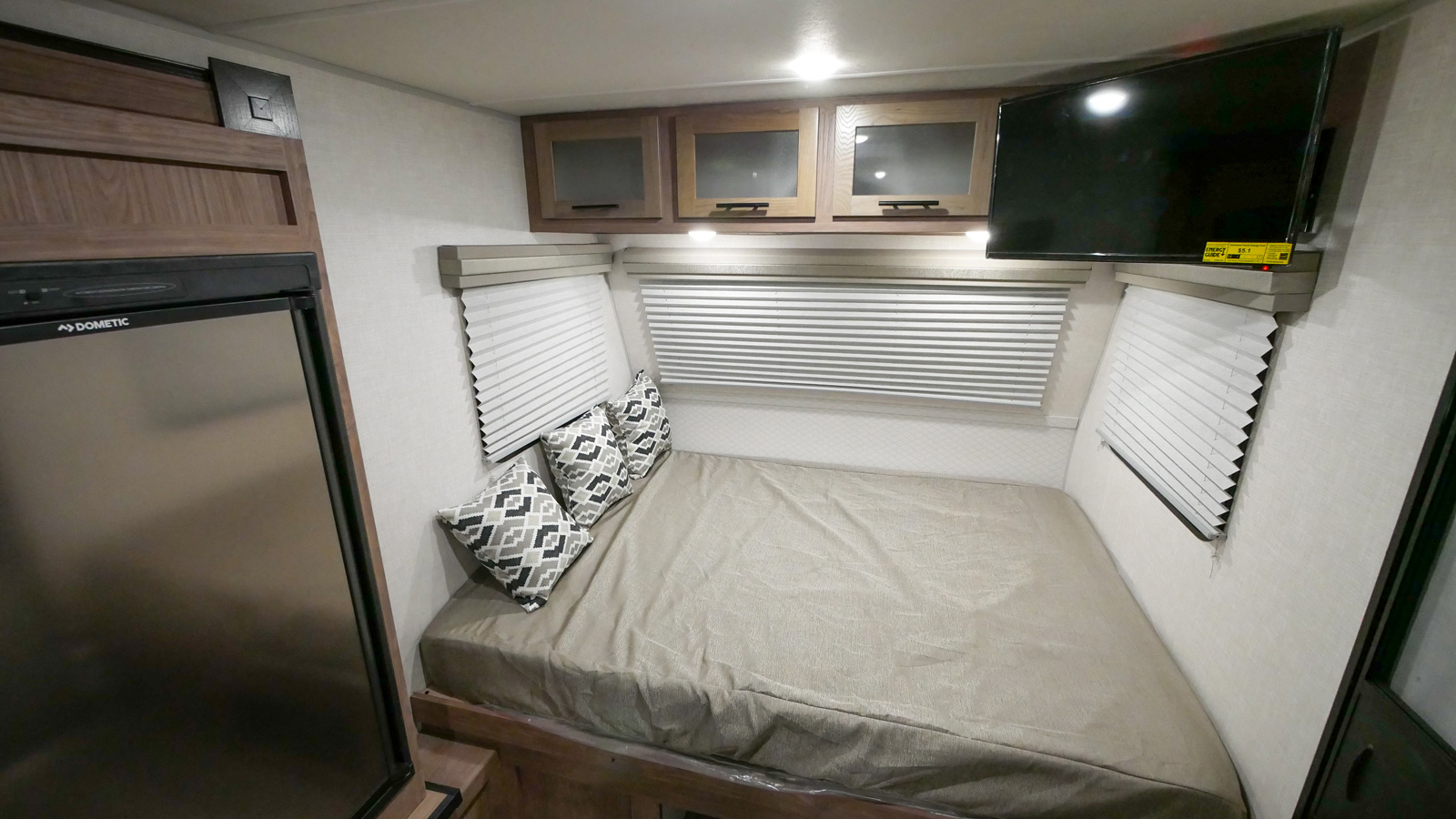 Queen bed, overhead cabinets, TV, and Dometic fridge furnish this cozy RV rental interior, ideal for travel.. Forest River No Boundaries 2021