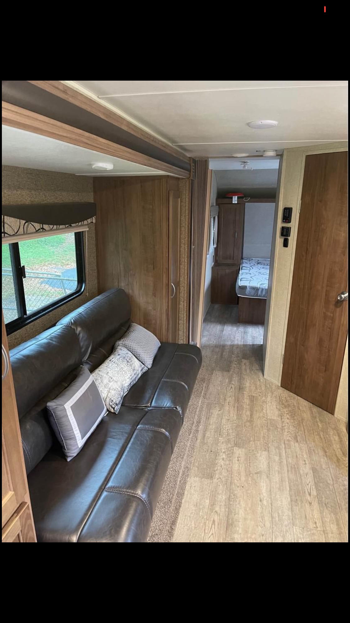 Tour this inviting RV rental interior! Features a dark sofa, wood accents, modern flooring, and a peek into the bedroom area.. Gulf Stream Amerilite 2018