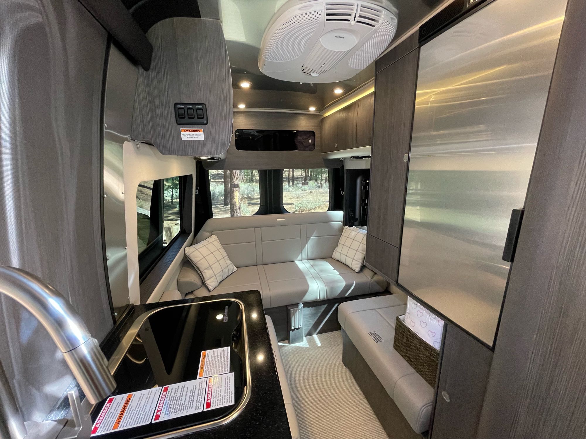 Bright, modern rv rental interior with kitchen, comfy sofa, fridge, and large windows. Enjoy scenic camper van travel!. Airstream Interstate 2021