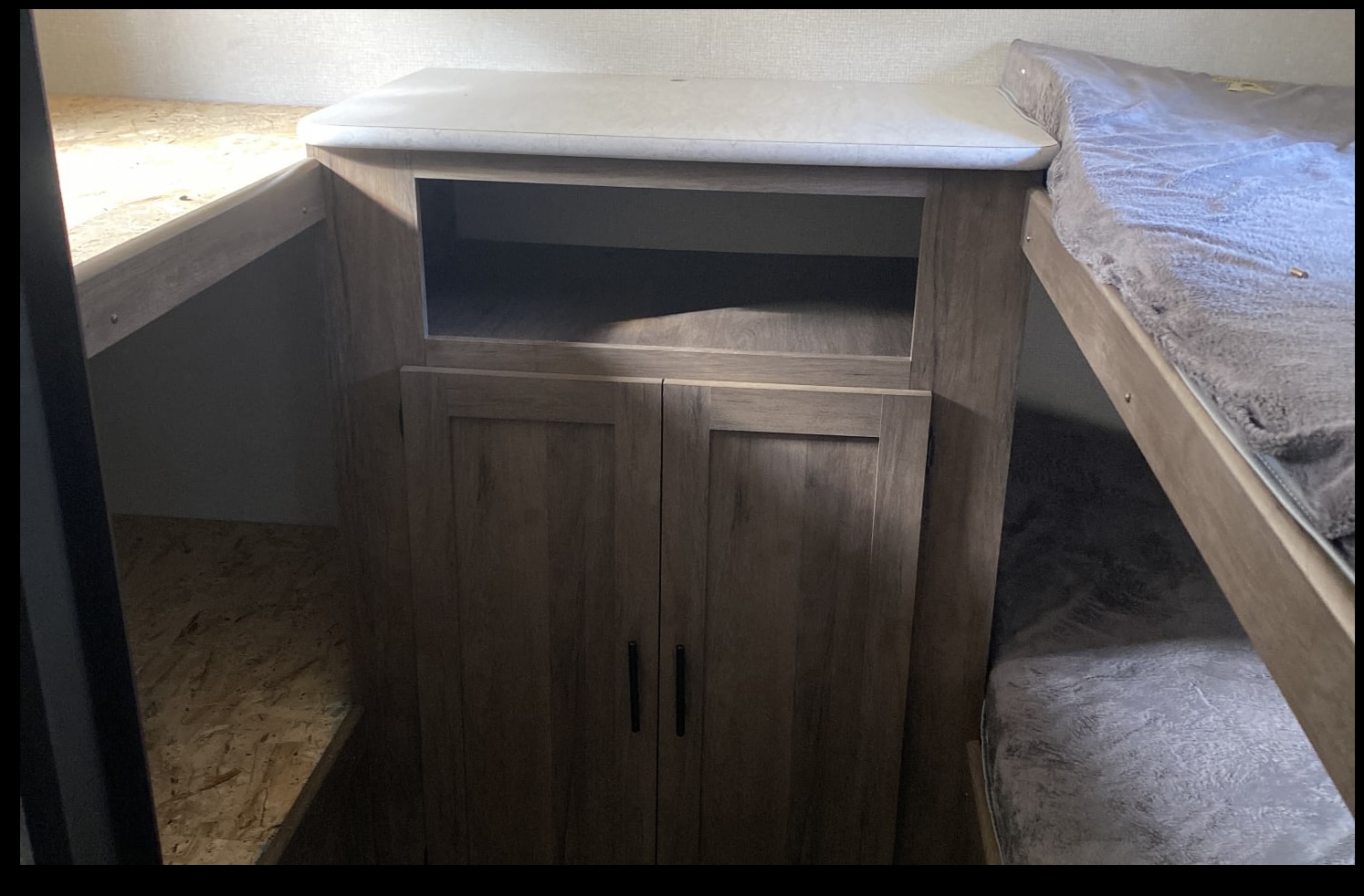 RV rental interior: upper & lower bunk beds, plus a storage cabinet with an open shelf & lower cupboard.. Forest River All American Sport 2020