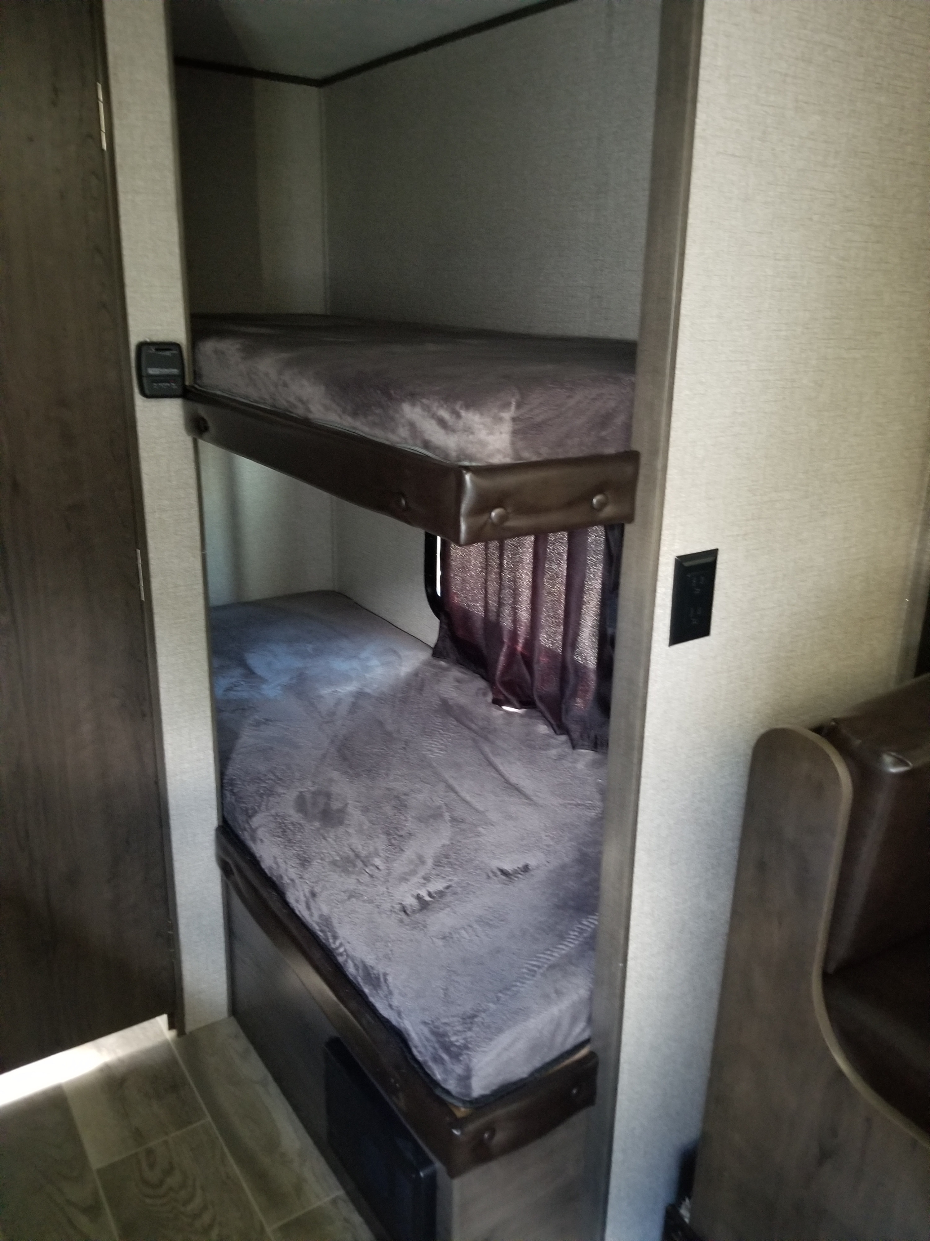 Bunk beds in an RV rental, offering a compact sleeping area with two comfy bunks and a privacy curtain, ideal for camper trips.. Jayco Jay Flight 2021