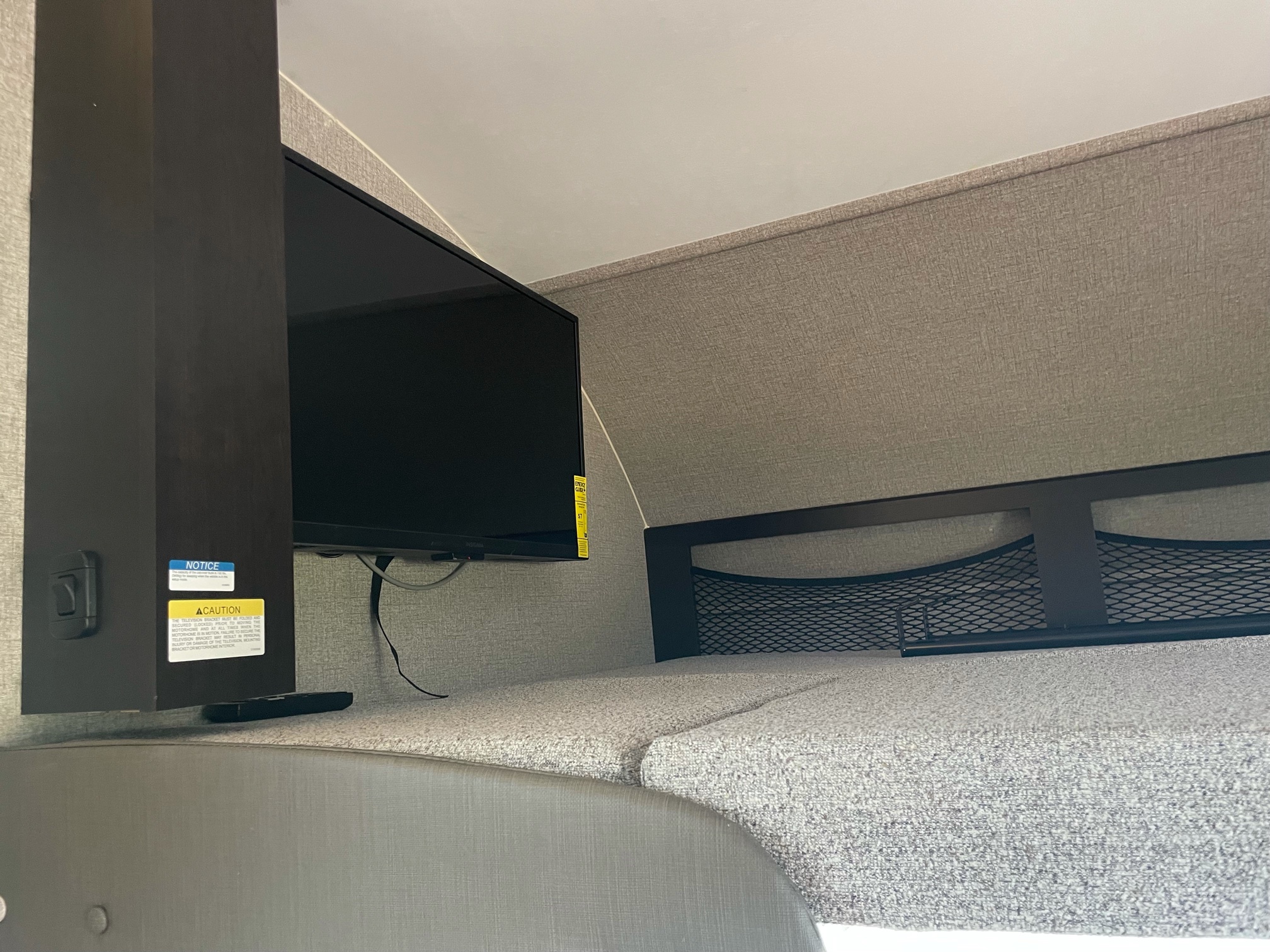 Cozy RV rental interior with a mounted TV, comfy bed cushions, and handy mesh storage net for travel.. Jayco Redhawk 2021