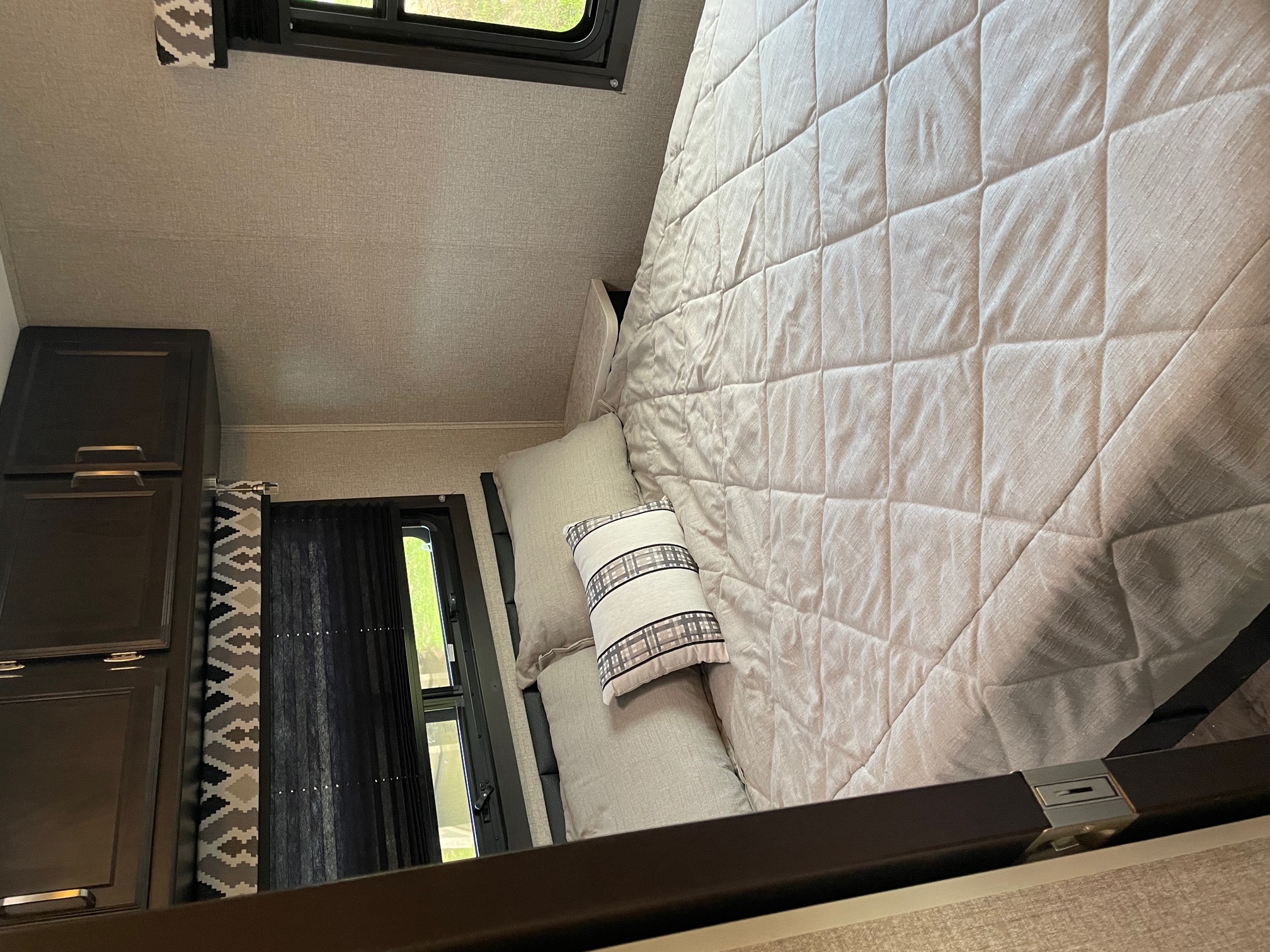 Cozy RV rental bedroom with a comfortable bed, textured walls, and a window for natural light. Perfect for travel.. Jayco Redhawk 2021