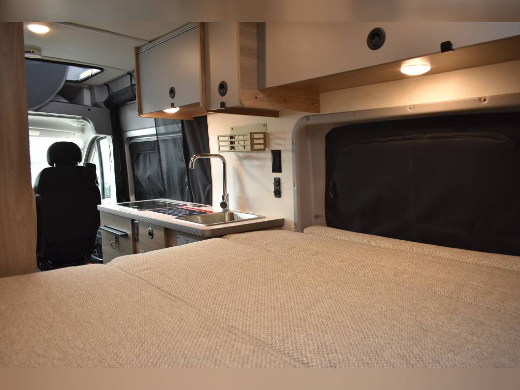 Cozy RV rental interior: comfortable bed and compact kitchen in a modern camper van, perfect for travel adventures.. Winnebago Other 2022