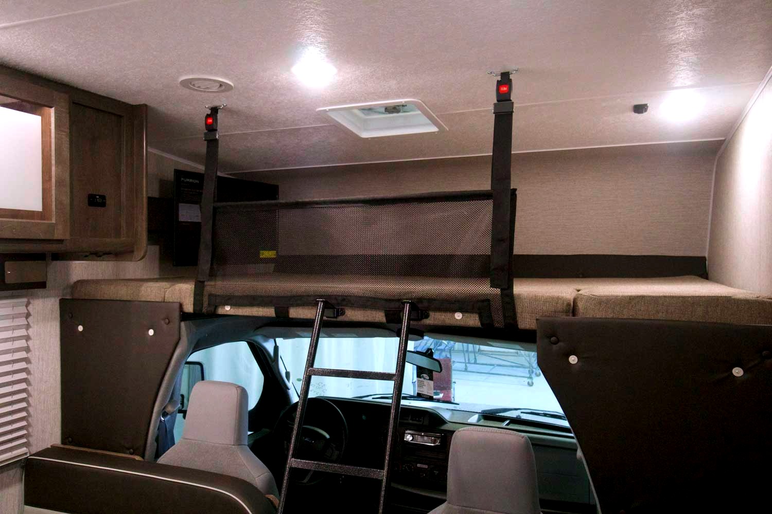 RV rental interior shows the cab-over bunk bed with a safety net and ladder, providing extra sleeping space.. Coachmen Leprechaun 2021