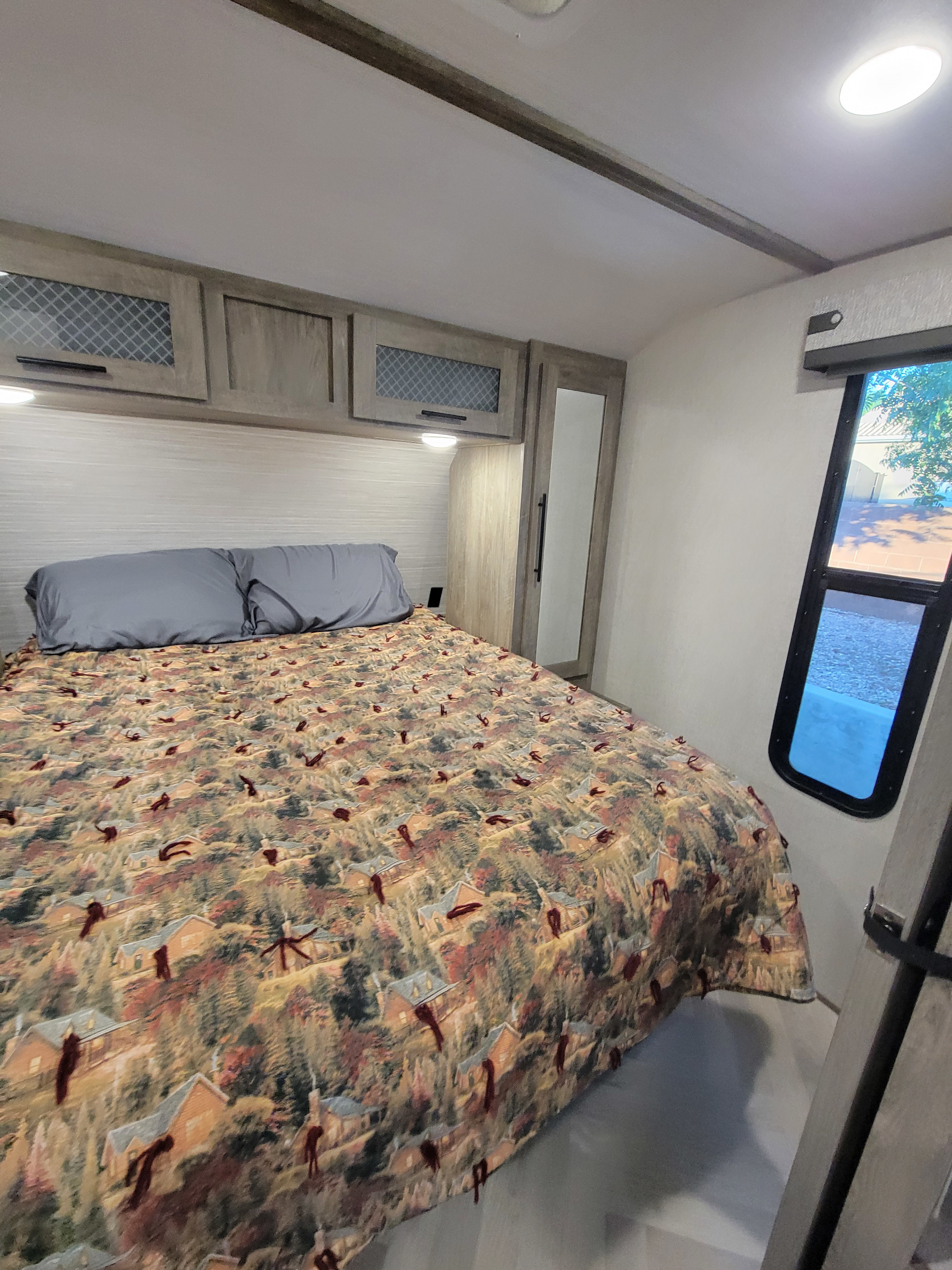 Comfortable RV rental bedroom with patterned comforter and overhead storage.. Forest River Wildwood Heritage Glen 2021