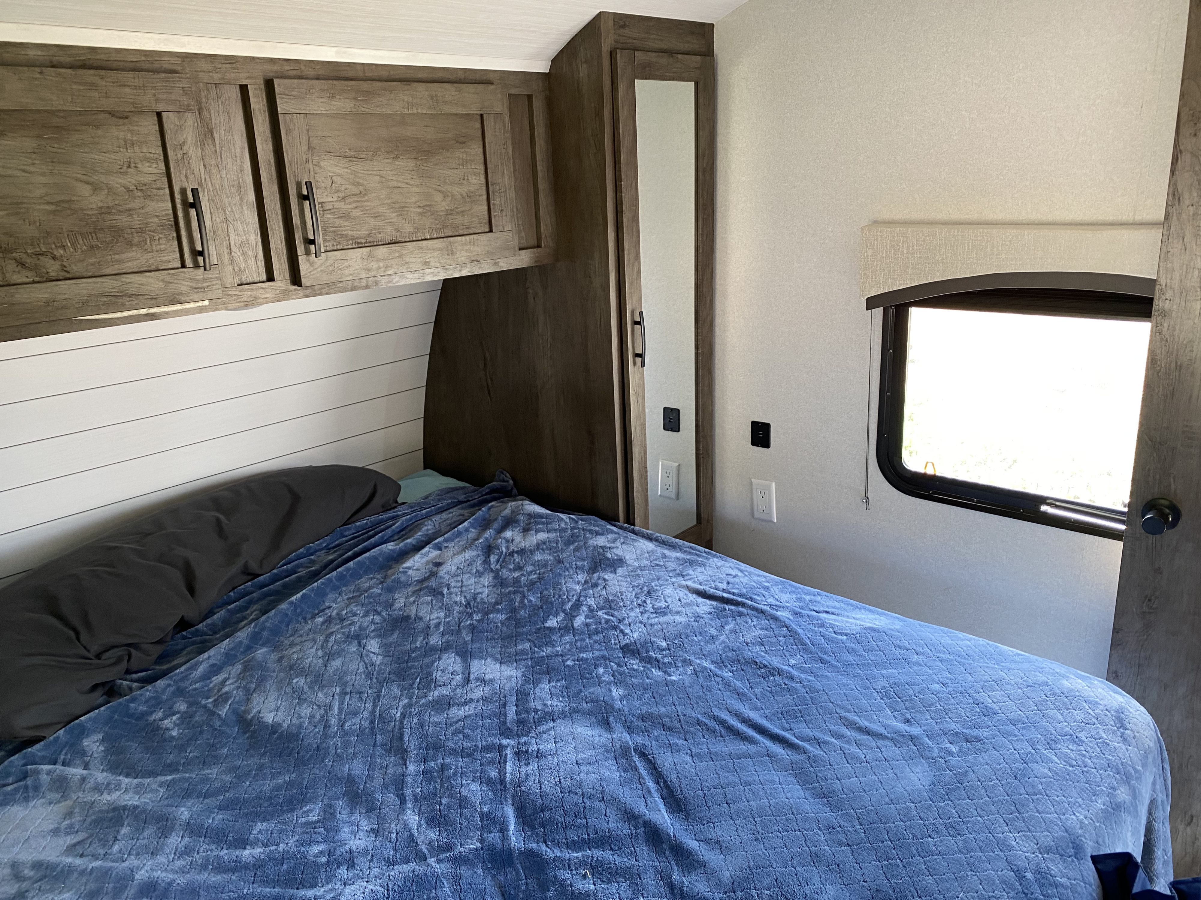 Cozy RV rental bedroom with a comfortable bed, overhead cabinets, and a mirrored wardrobe.. Forest River Evo 2020