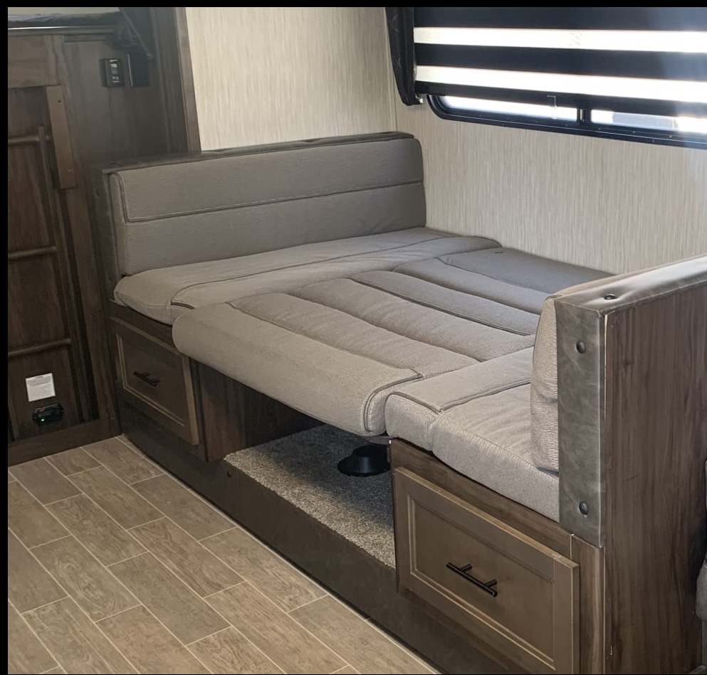 Check out this RV rental's versatile interior! A dinette with gray cushions transforms into a comfy bed, with wood storage.. Forest River Other 2021