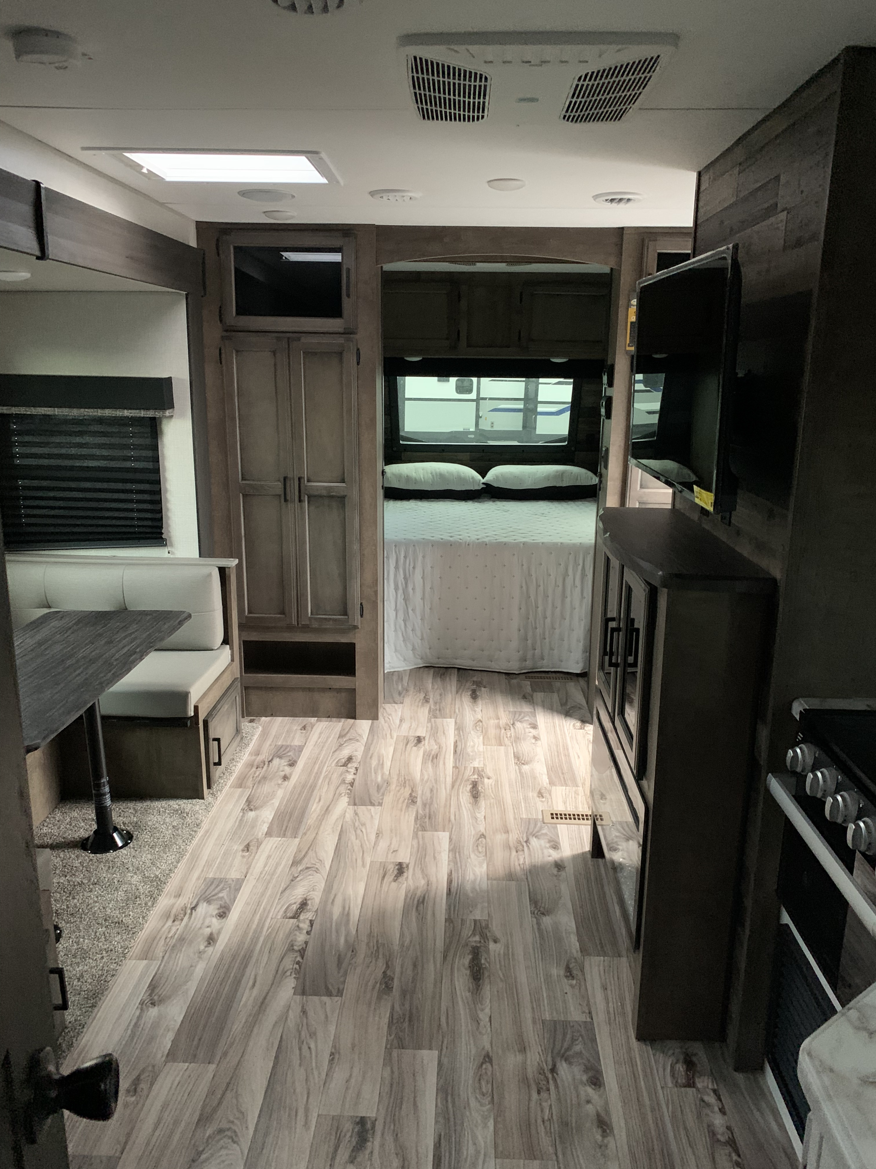 Inside this RV rental, discover a bright living space with wood-look floors leading to a dining booth, kitchen, and cozy private bedroom.. Venture Rv Sporttrek 2022