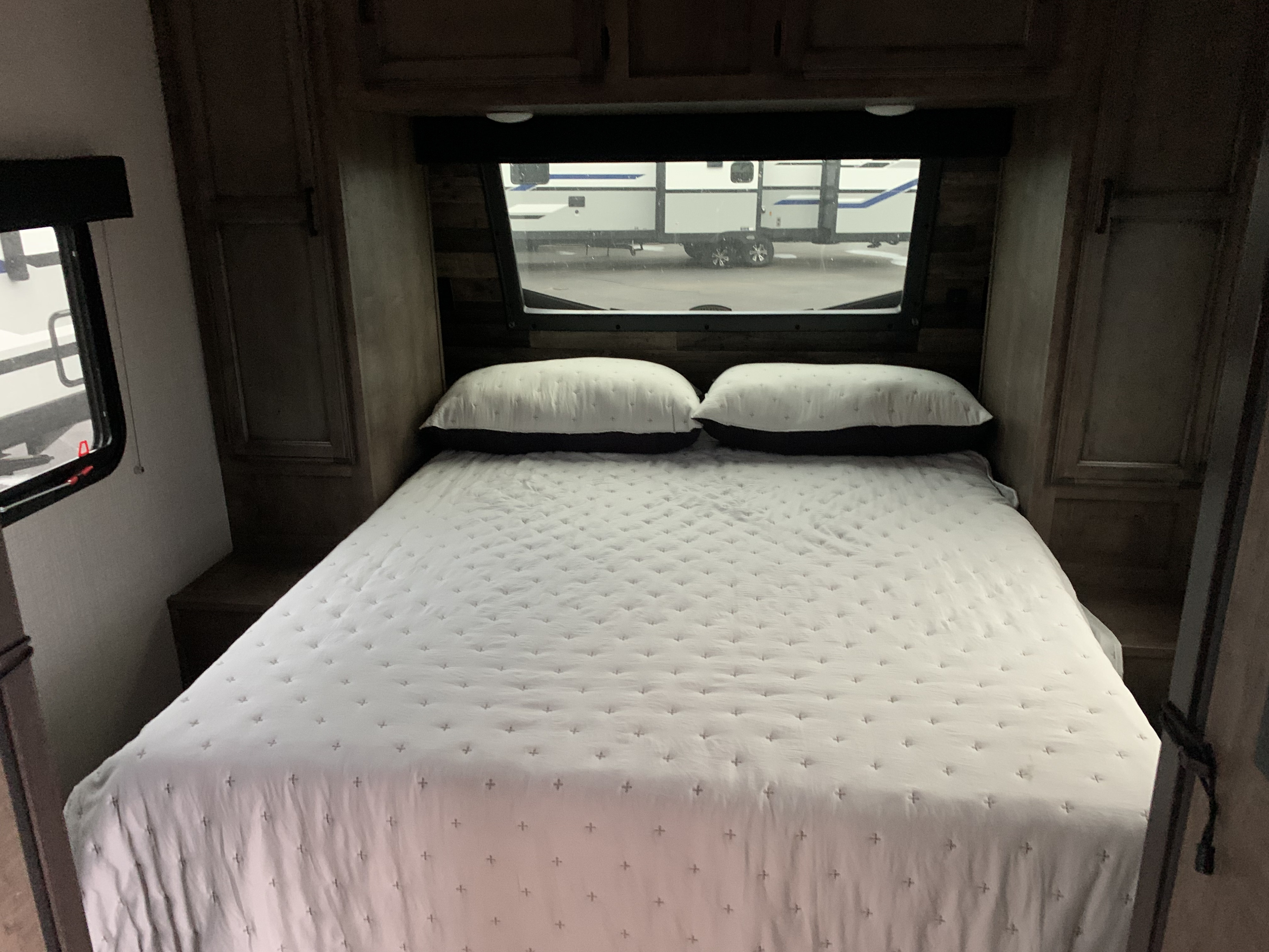 RV rental bedroom: a cozy interior featuring a large bed with pillows and a window view of other RVs.. Venture Rv Sporttrek 2022