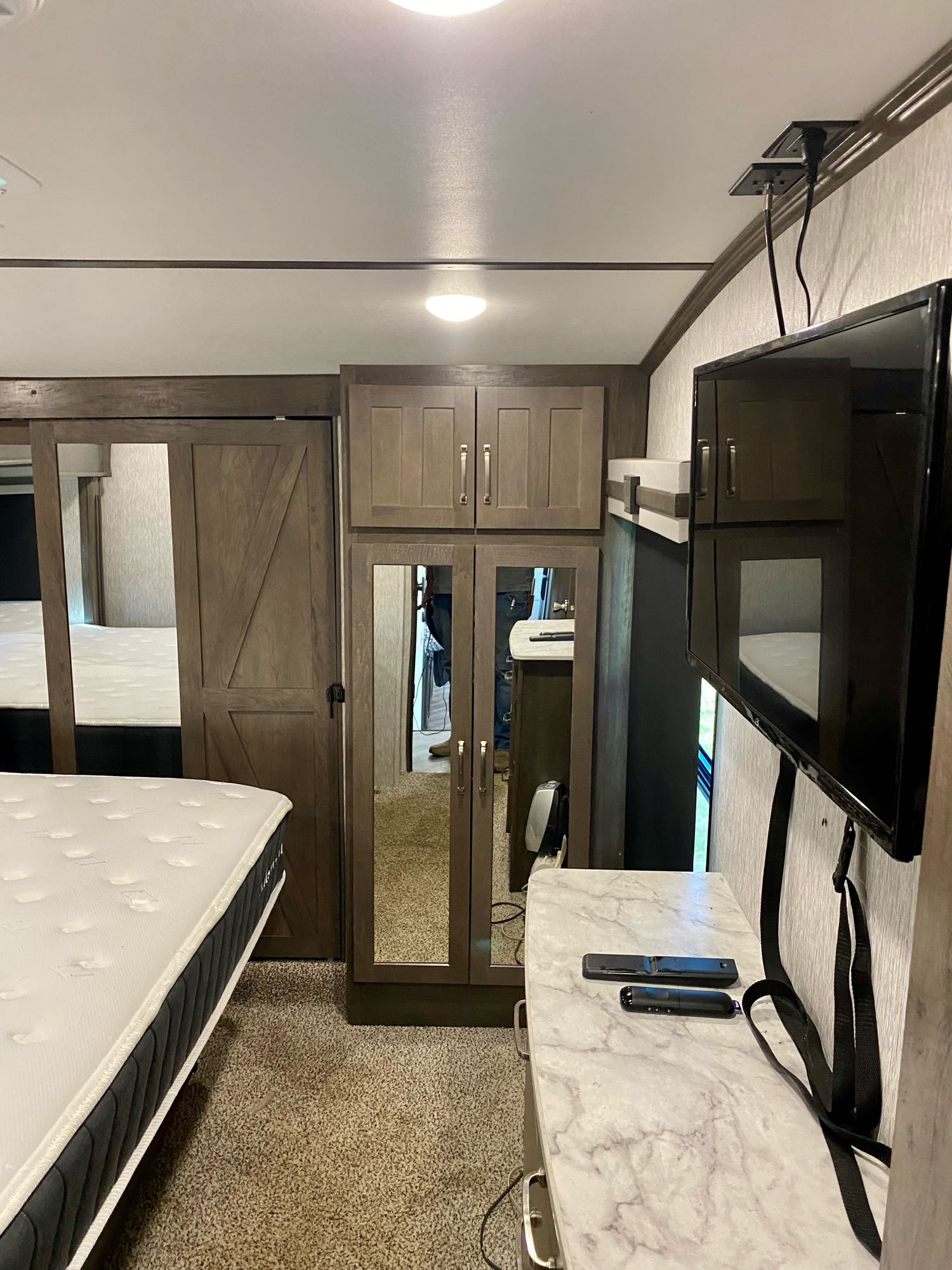 Experience comfort in this modern RV rental bedroom, featuring a queen bed, TV, and ample storage cabinets.. Dutchmen Other 2021