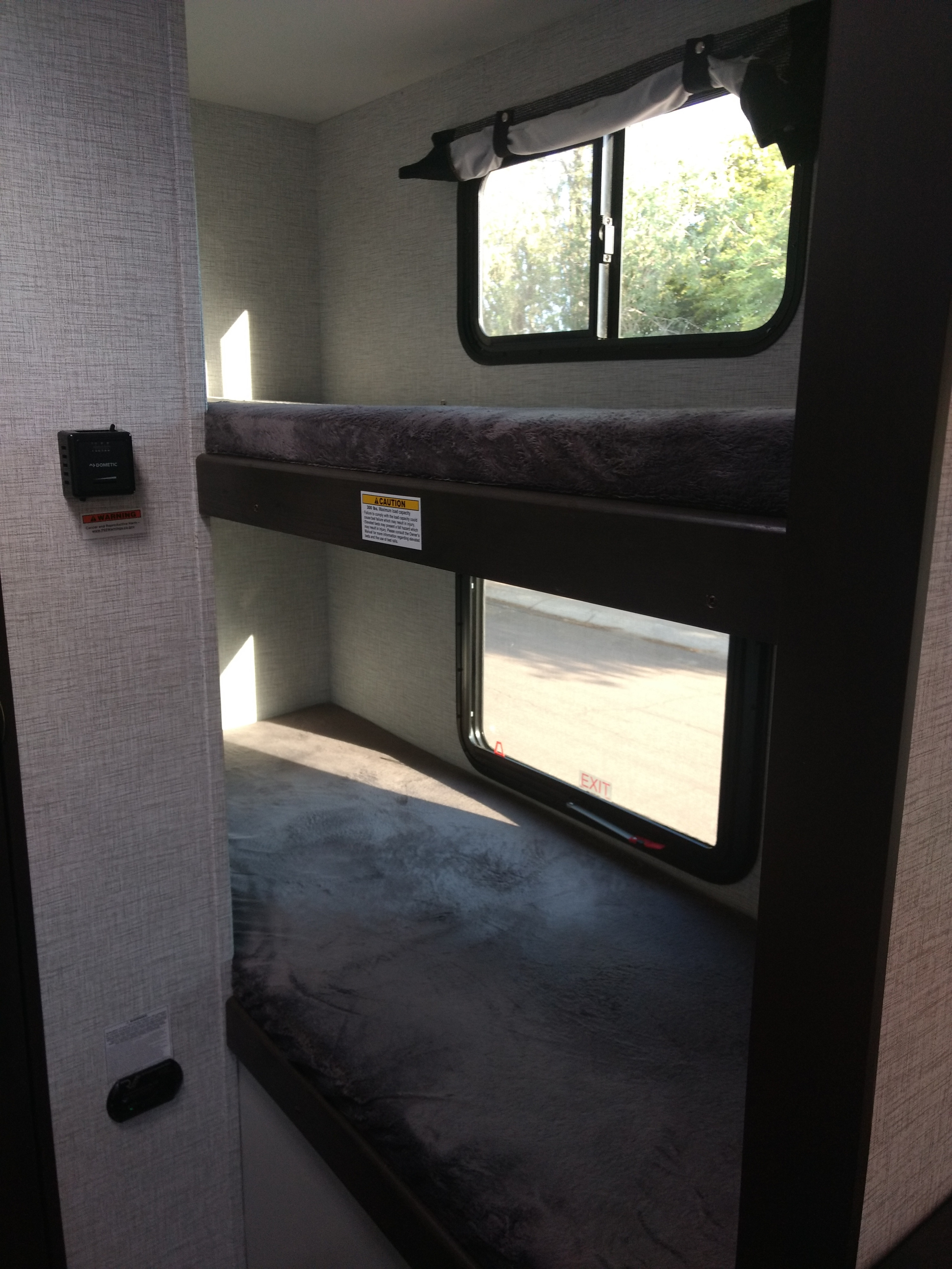 Compact RV rental interior showing bunk beds, windows, and light gray walls. Ideal for family adventures.. Keystone RV Bullet Crossfire 2021