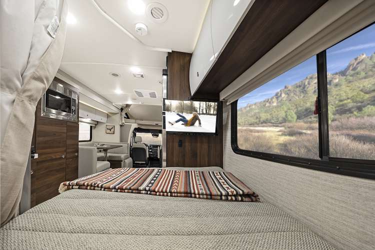 Cozy rv rental interior: Bedroom with TV, microwave, and a scenic mountain view outside the large window.. Winnebago View 2022