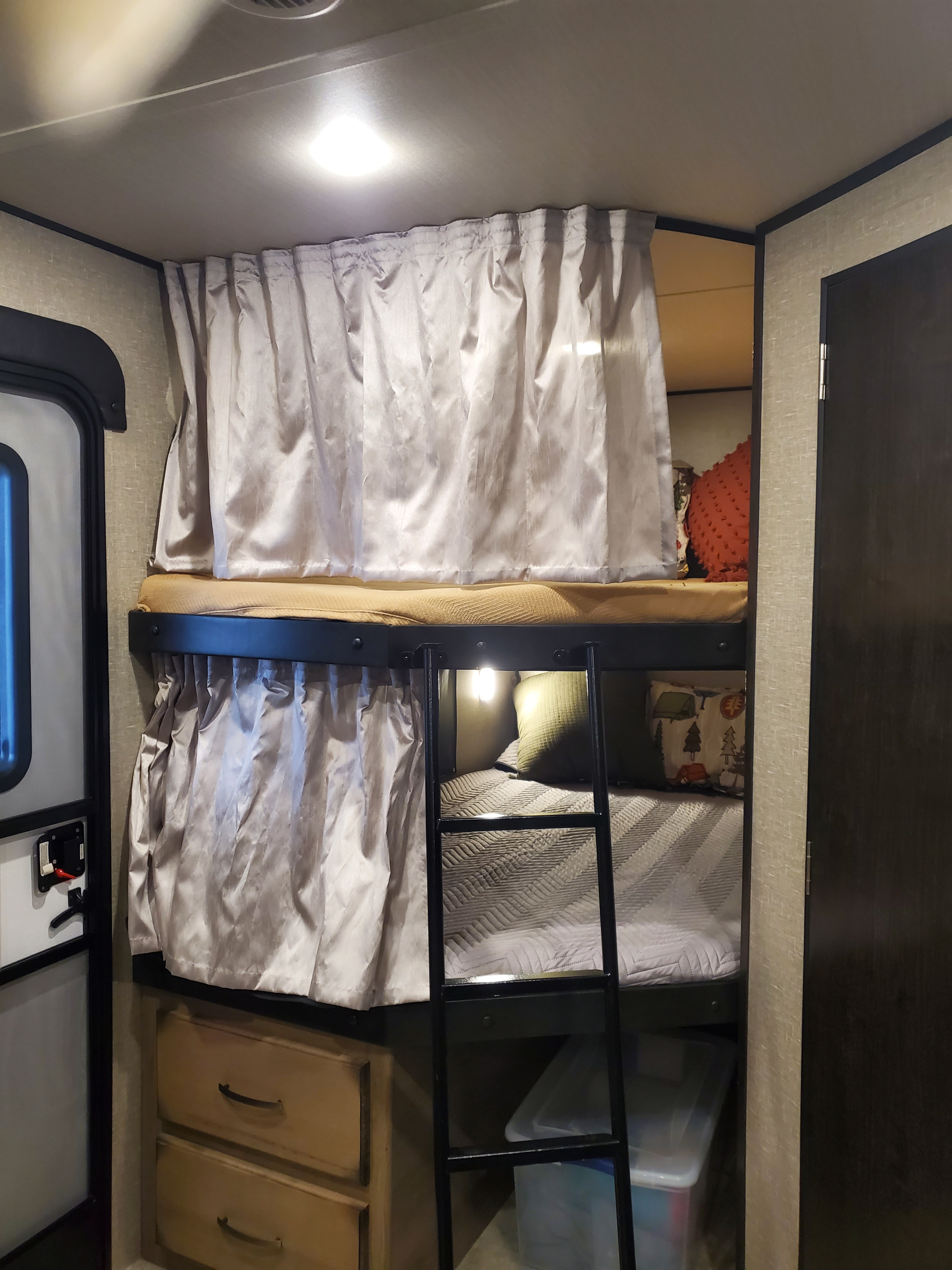 Inside an RV rental: cozy bunk beds with privacy curtains, a ladder, and storage.. Grand Design Transcend 2019