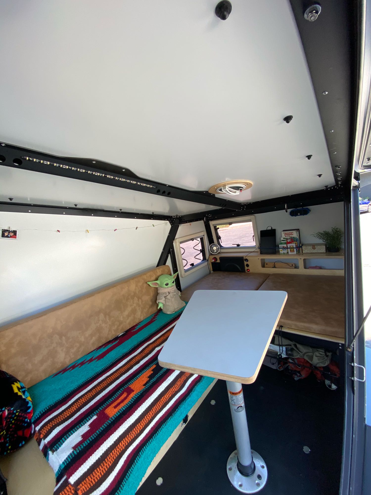 Explore this cozy RV rental interior with a bench, table, bed, Grogu, and ample storage for your next adventure.. TAXA Outdoors Tigermoth Camper 2021