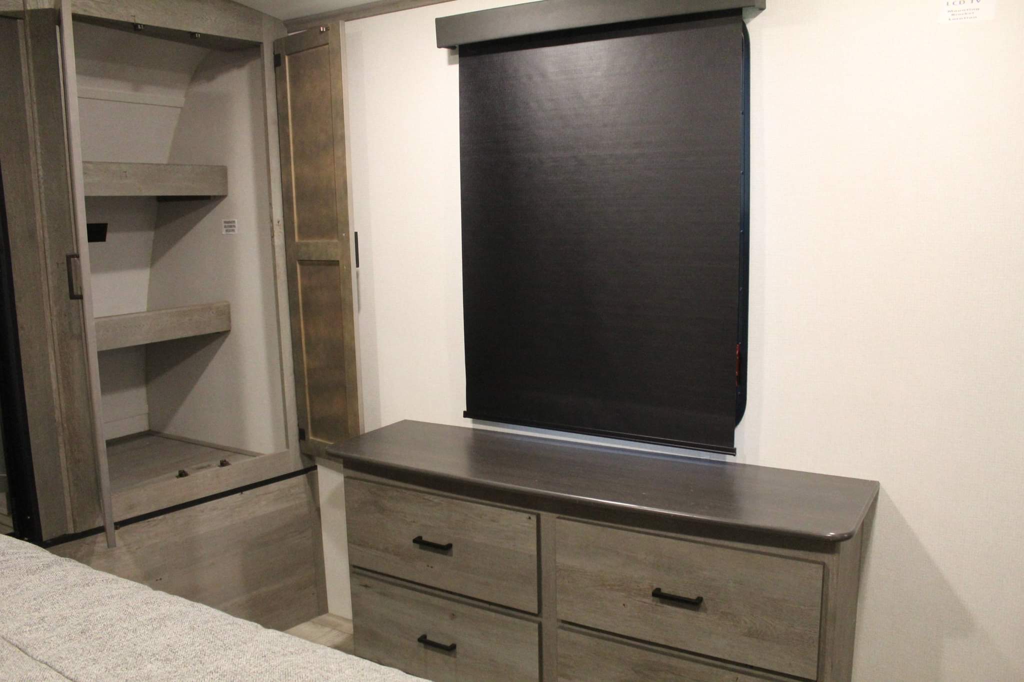RV rental bedroom featuring a built-in wardrobe, a dresser with storage, and a blackout window shade.. Keystone RV Outback 2021