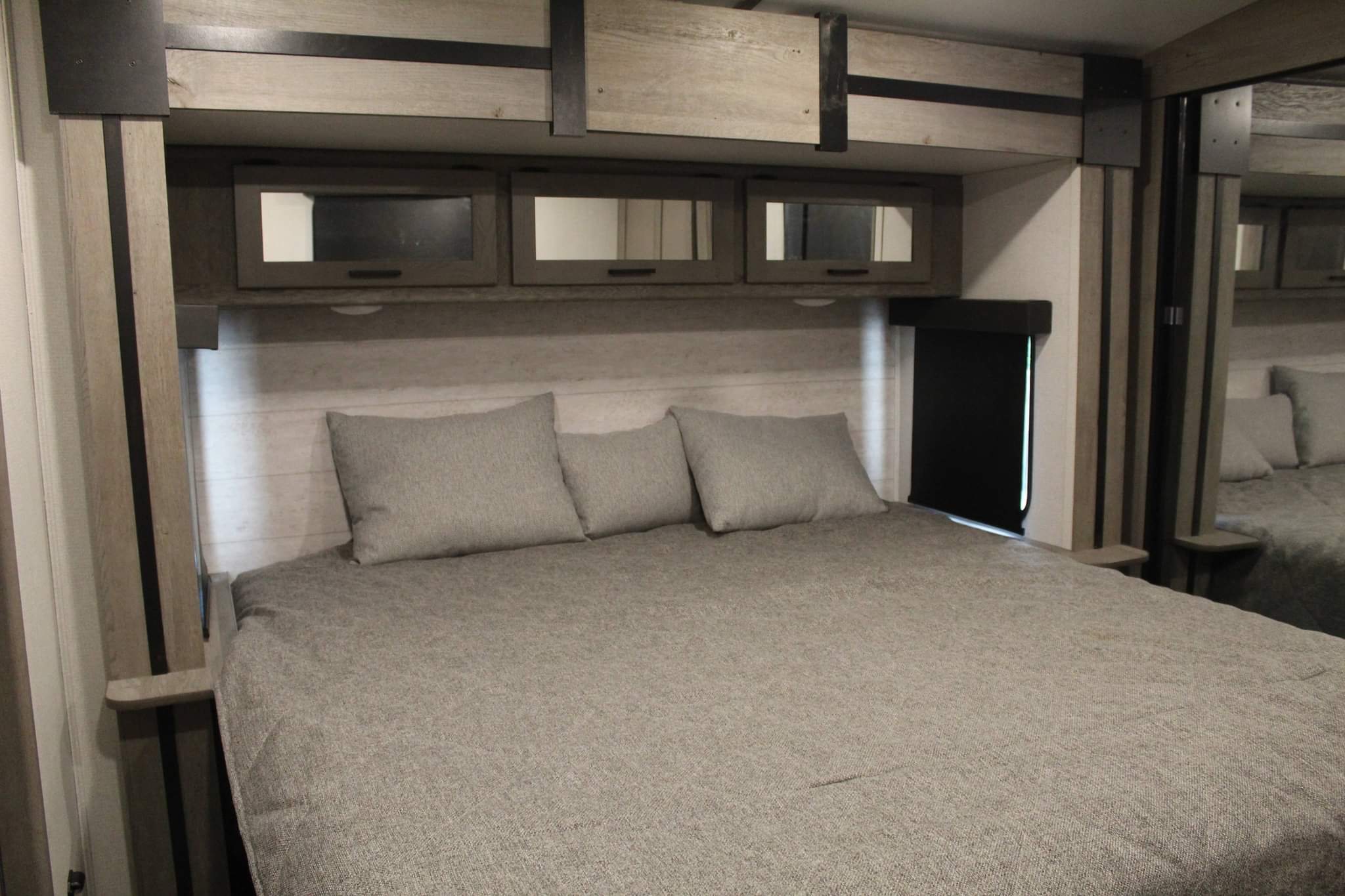 Comfortable RV rental bedroom featuring a cozy bed, overhead storage, and modern light wood decor.. Keystone RV Outback 2021