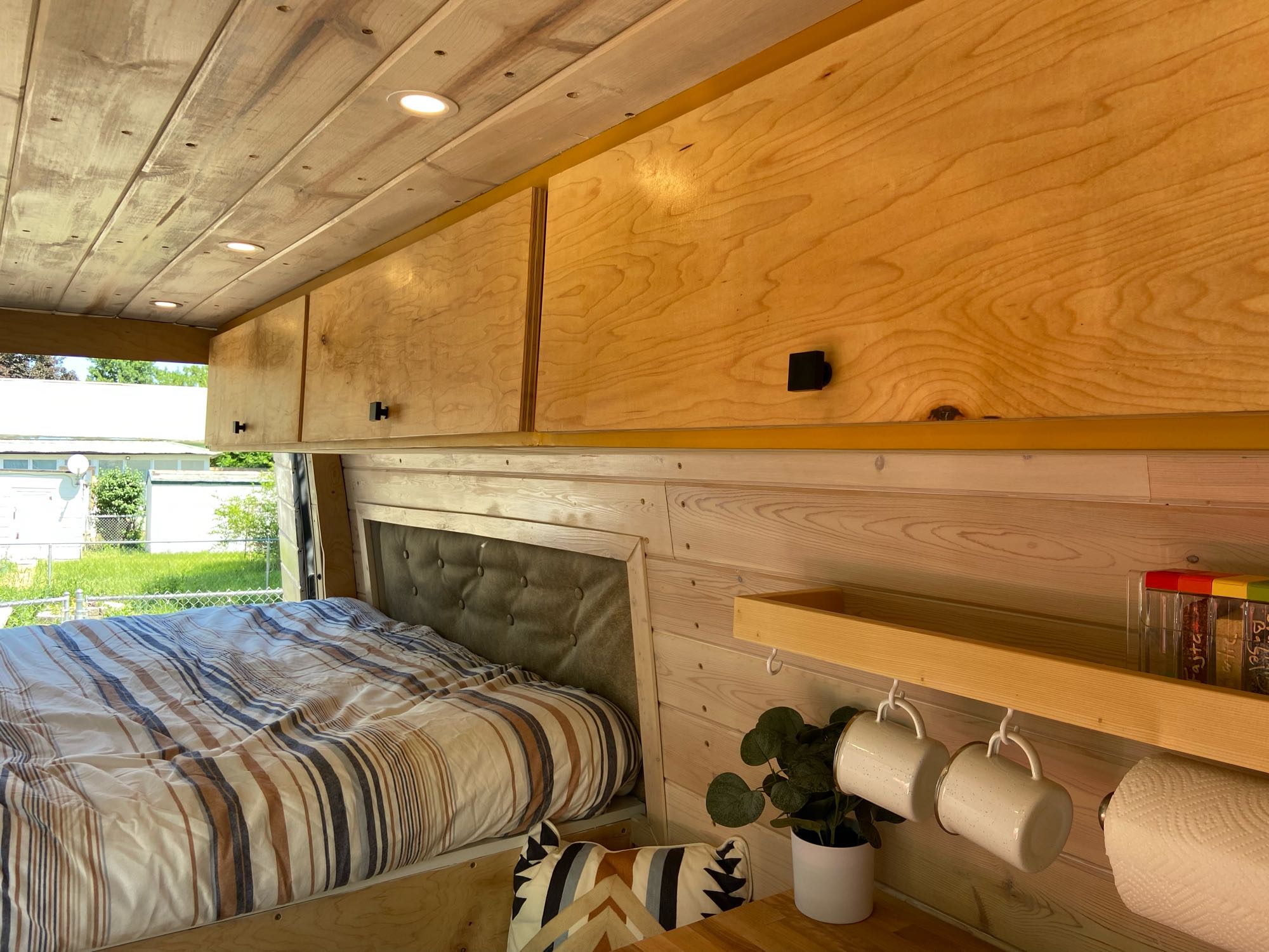 Cozy RV rental interior: wooden walls/ceiling, storage cabinets, bed with striped bedding, and mini kitchenette area.. Freightliner Sprinter 2009