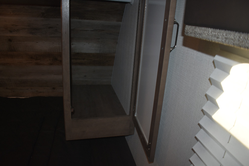 RV rental: Open cabinet with light interior for storage, next to wood-look walls and a bright window with pleated blinds.. Keystone Passport 2021