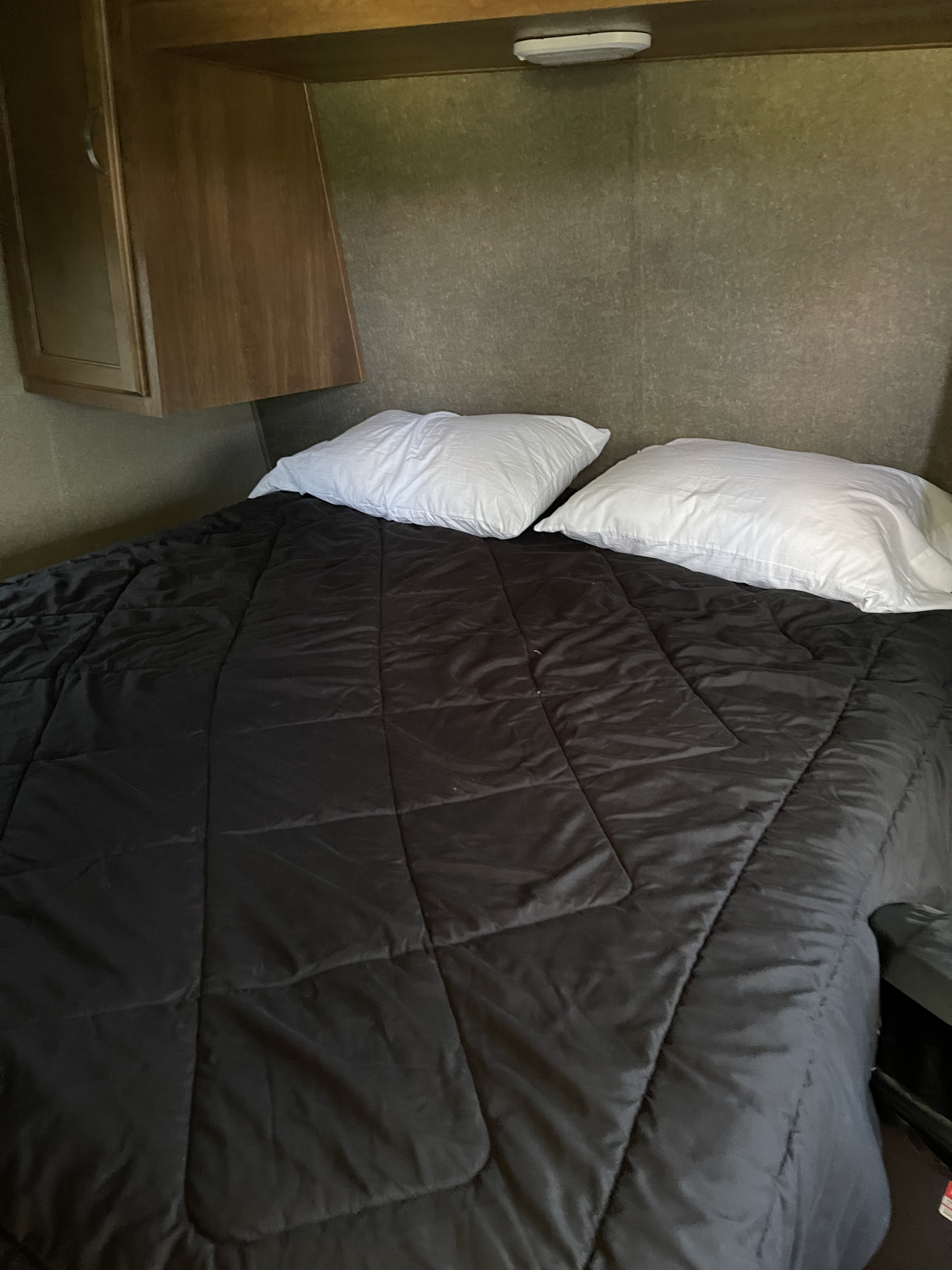 Comfortable bed in an RV rental with a black comforter and white pillows, perfect for a cozy night's stay.. Keystone Summerland 2017