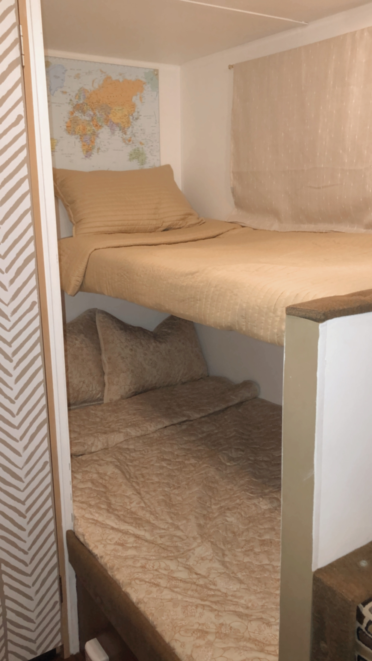 Cozy RV rental bunk beds with beige quilted bedding, a world map, and window curtain, providing comfortable sleeping.. Wildwood 32qbss Wildwood Xlite 2014