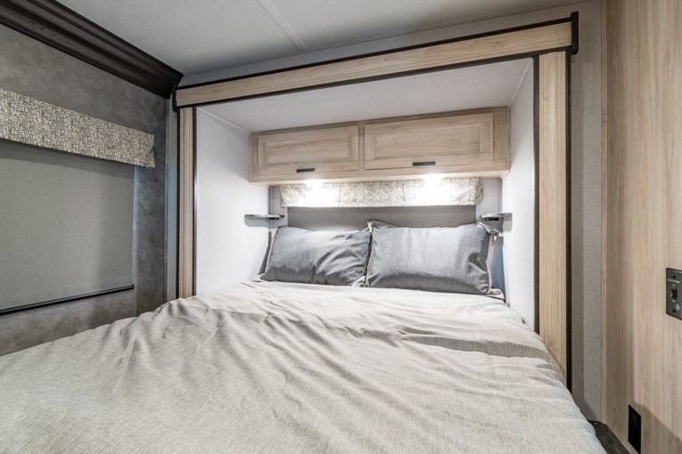 Inside an RV rental: a modern bedroom with a comfortable bed, light wood cabinets, reading lights, and neutral decor.. Forest River Forester LE 2251SLEF 2021