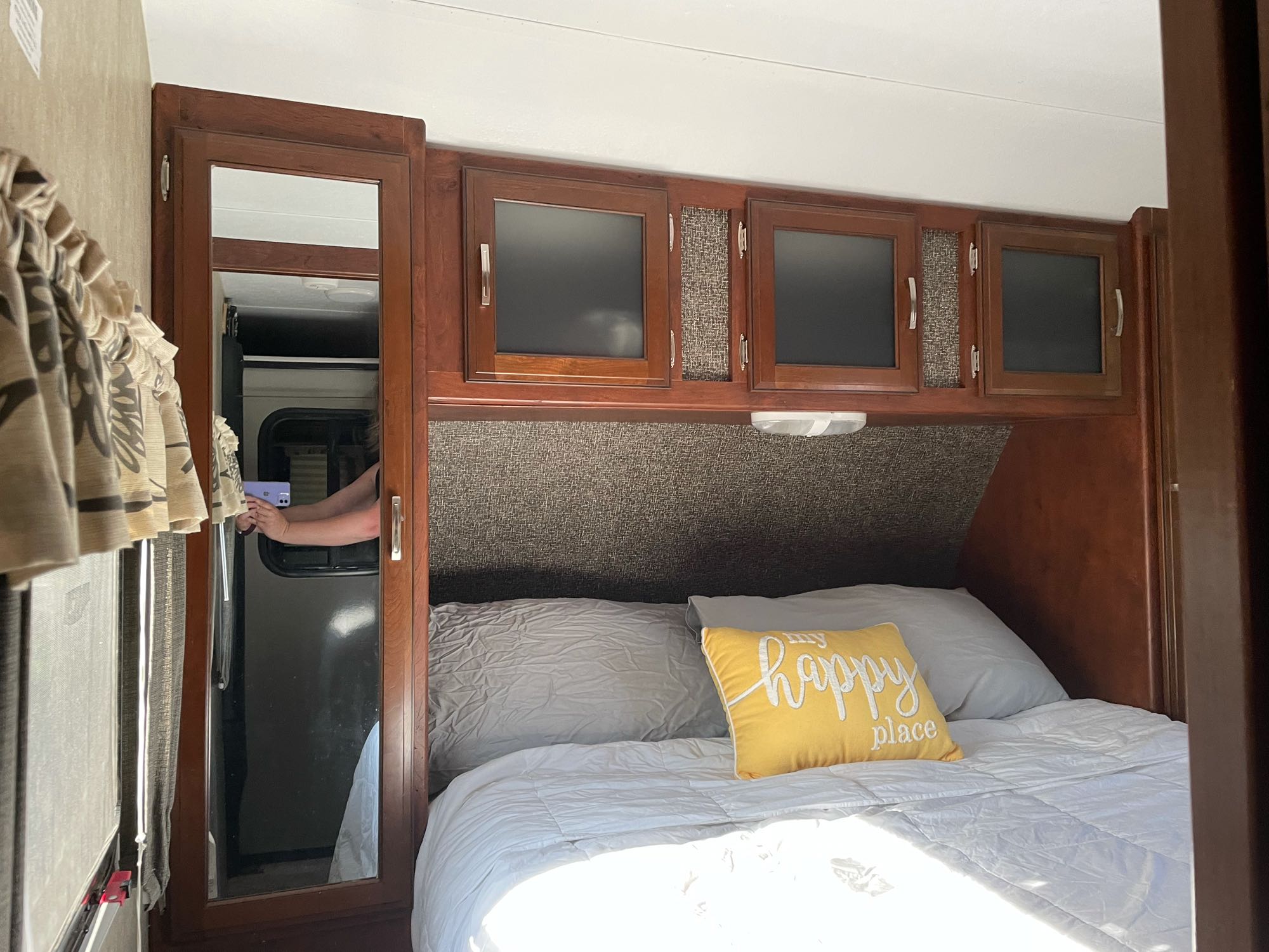 Cozy RV rental bedroom interior, featuring a comfy bed, cheerful pillow, and ample overhead storage for travel.. Keystone Passport 2016