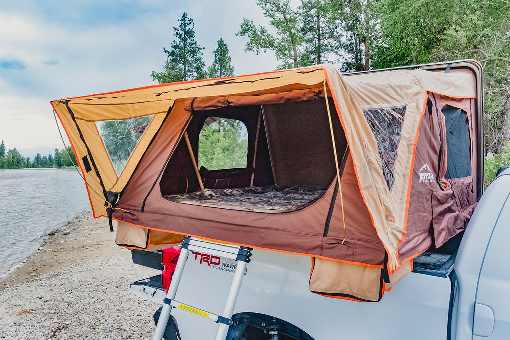 Discover outdoor adventures! This open brown rooftop tent on a white pickup by a lake offers cozy camping, a unique RV rental alternative.. Toyota Tundra 2011