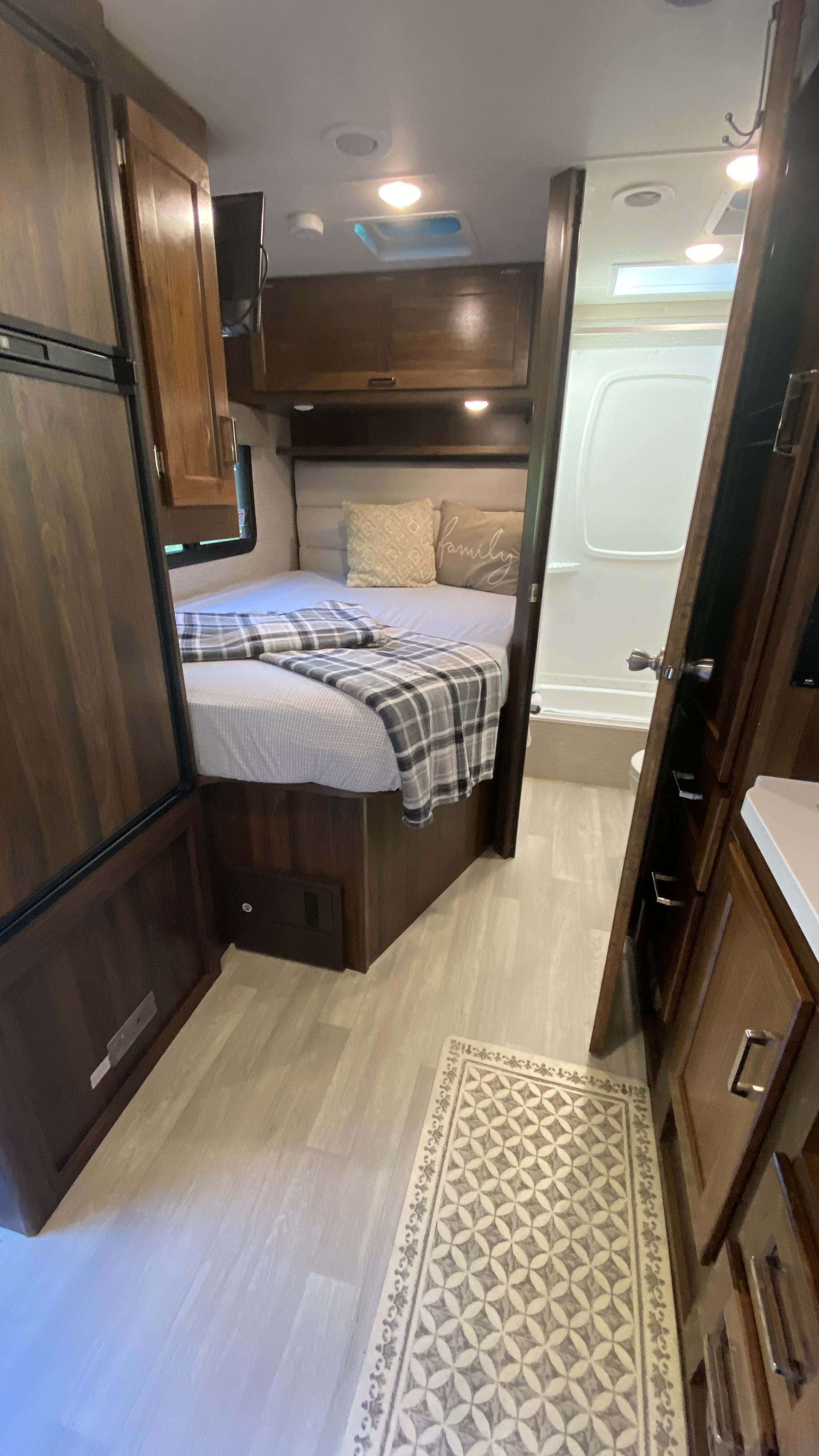 Compact RV rental interior featuring a cozy bedroom area with bed, TV, and a functional bathroom, ideal for travel adventures.. Winnebago Minnie Winnie 2020