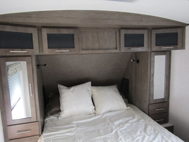 Cozy RV rental bedroom with a comfortable bed, practical overhead cabinets, and mirrored wardrobes for efficient storage.. Forest River Surveyor 2019